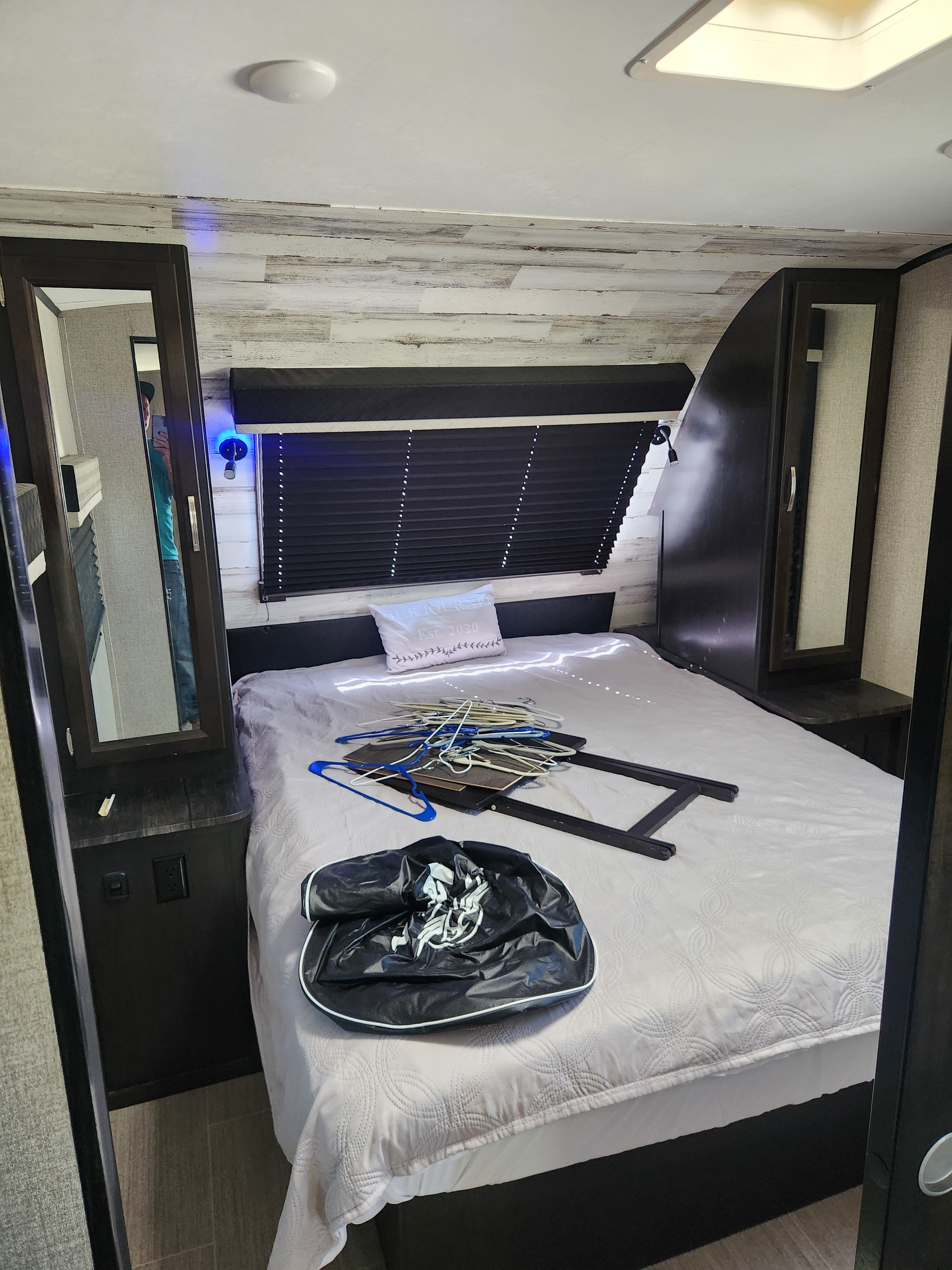 RV rental bedroom featuring a bed with hangers, mirrored closets, and blue accent lighting.. Jayco White Hawk 2020