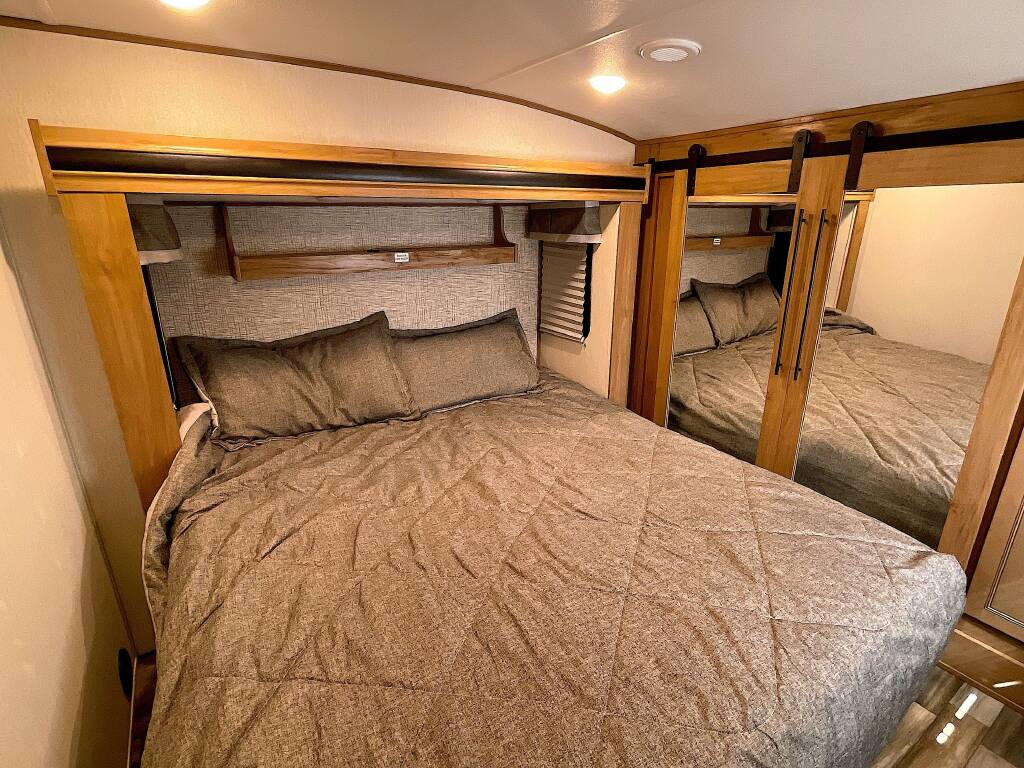 Comfortable RV rental bedroom with a cozy bed and mirrored closet, perfect for travel.. Forest River Sabre 2024