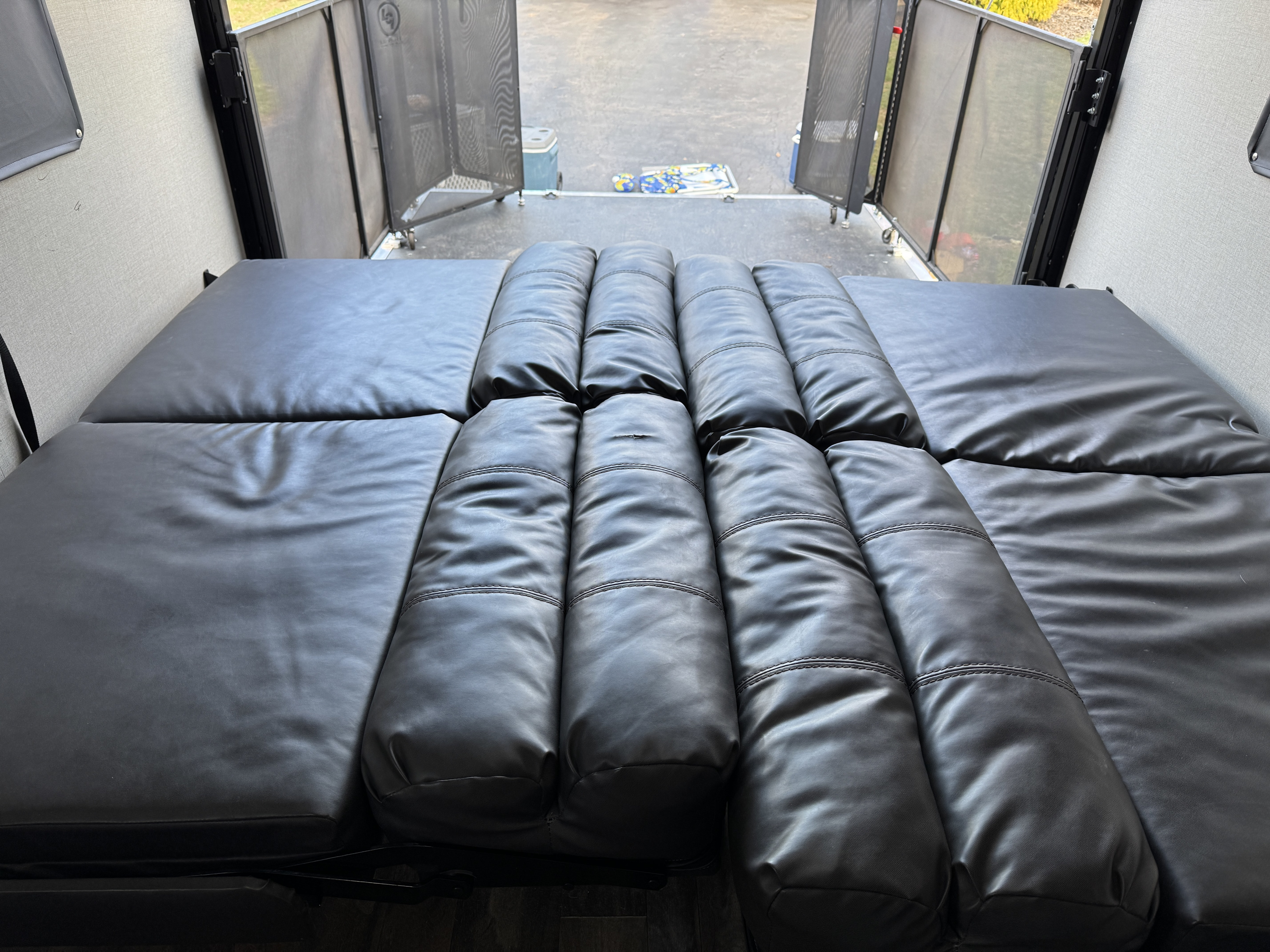 RV rental interior: Plush black convertible seating/bed, with an open rear ramp and mesh screen doors.. Coachmen Catalina 2021