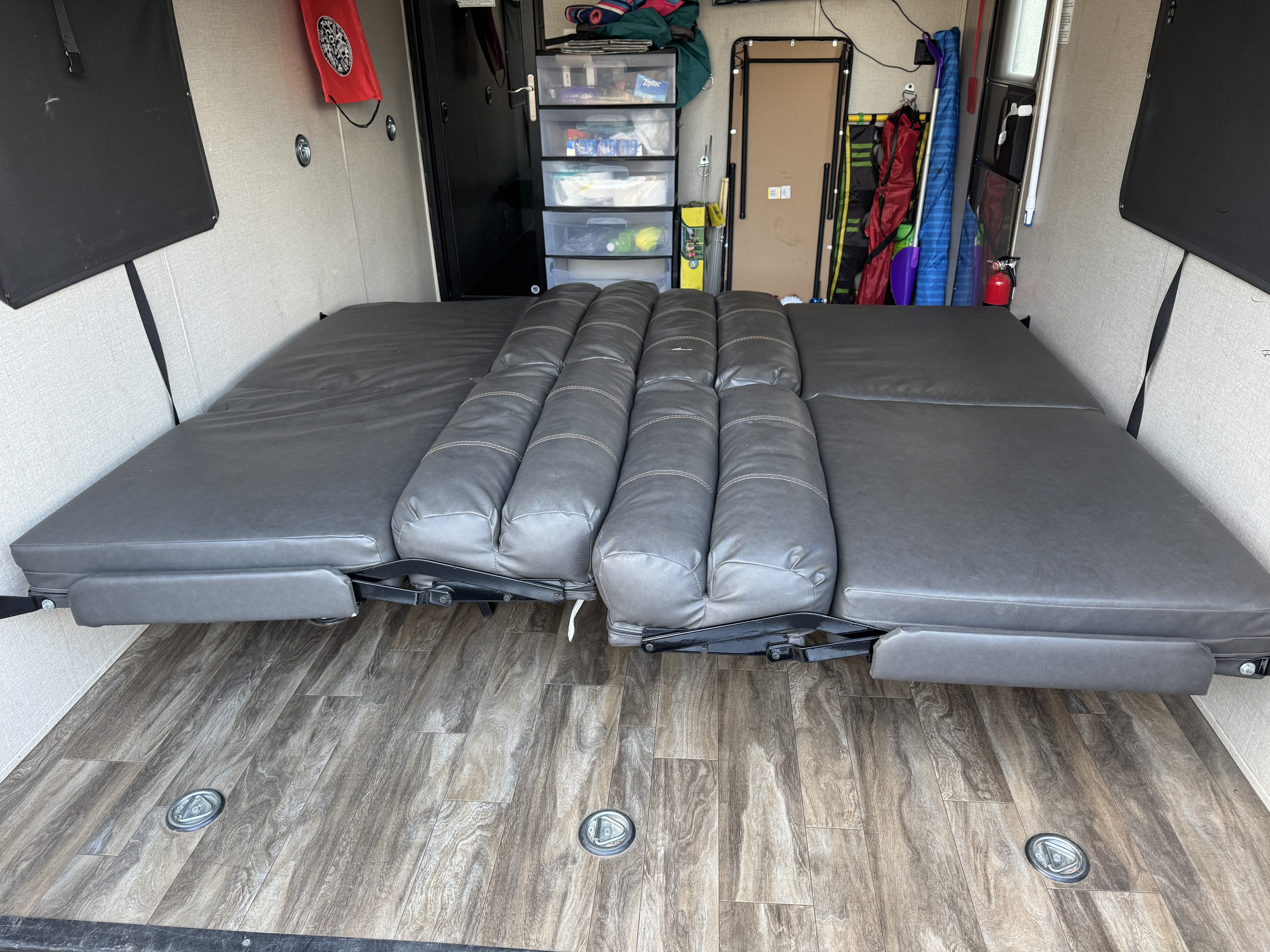 Comfortable RV rental interior: gray sofa-bed, wood-style floor with tie-downs, and organized storage.. Coachmen Catalina 2021