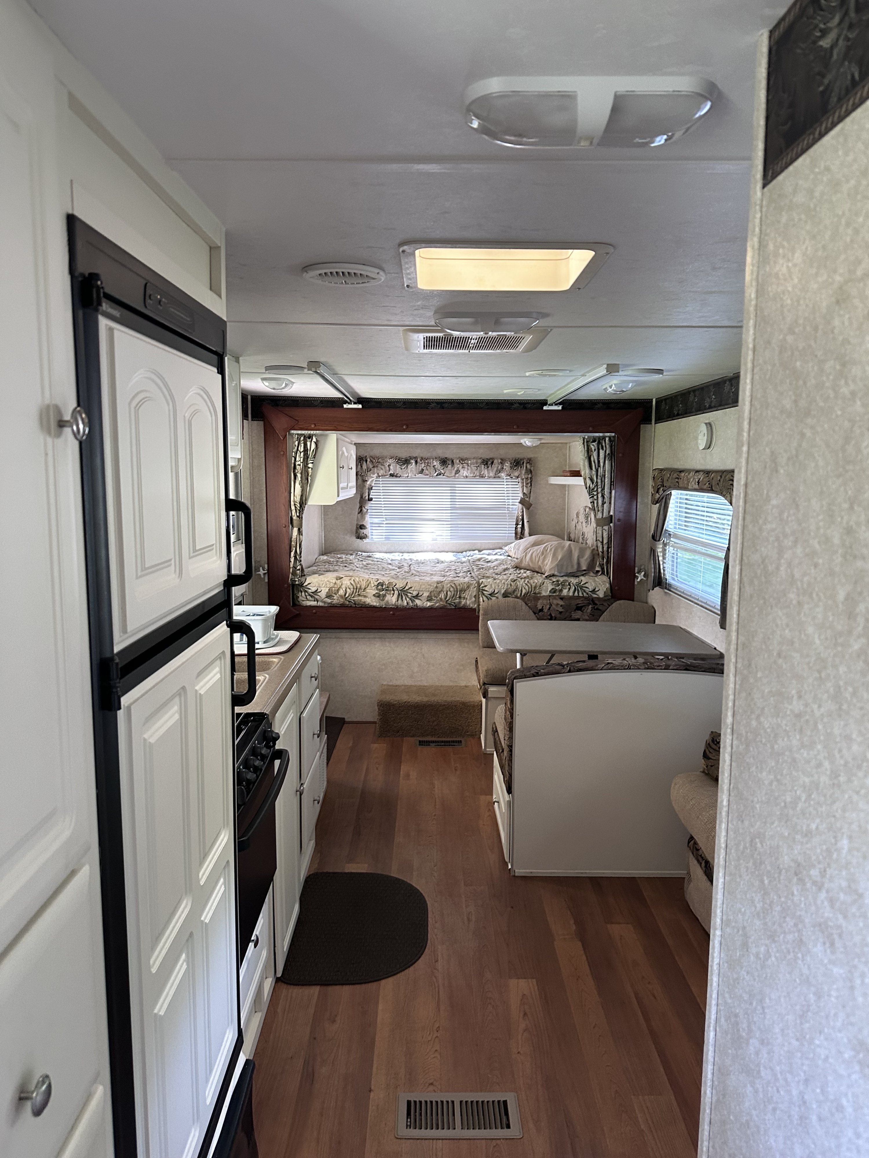 Bright RV rental interior with kitchen, dining booth, and bedroom. Features fridge, stove, and dinette.. Keystone RV Outback 2007