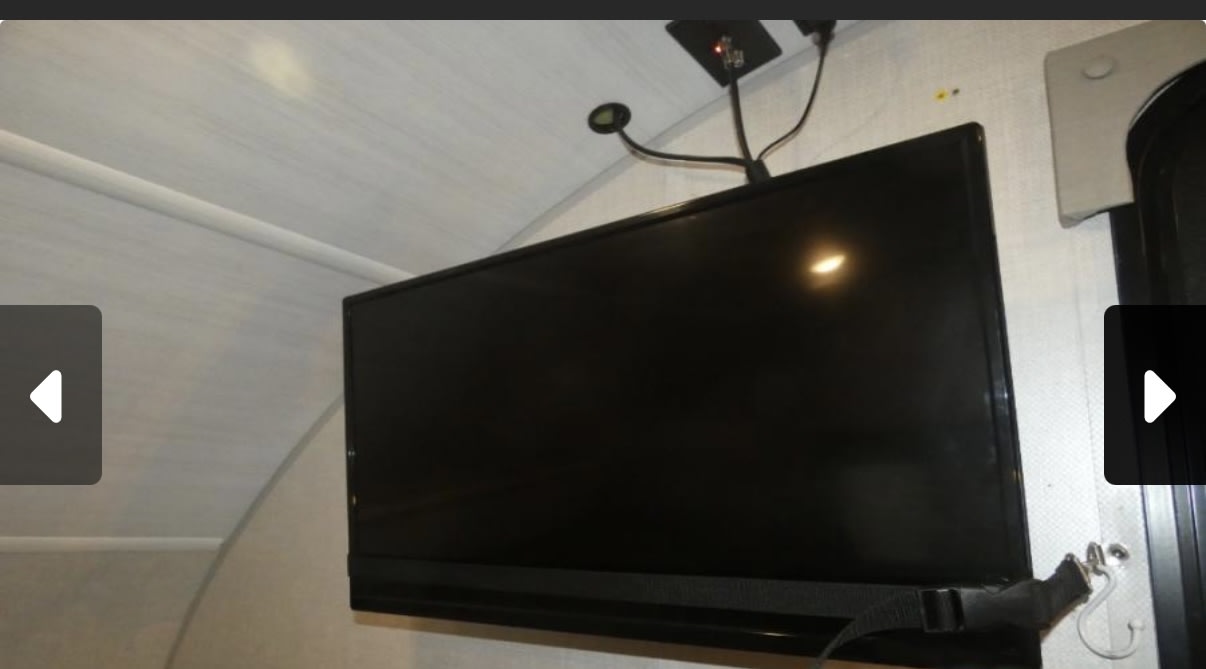 RV rental amenity: a wall-mounted flat-screen TV with a flexible reading light and securing strap for travel.. Forest River R pod 2022