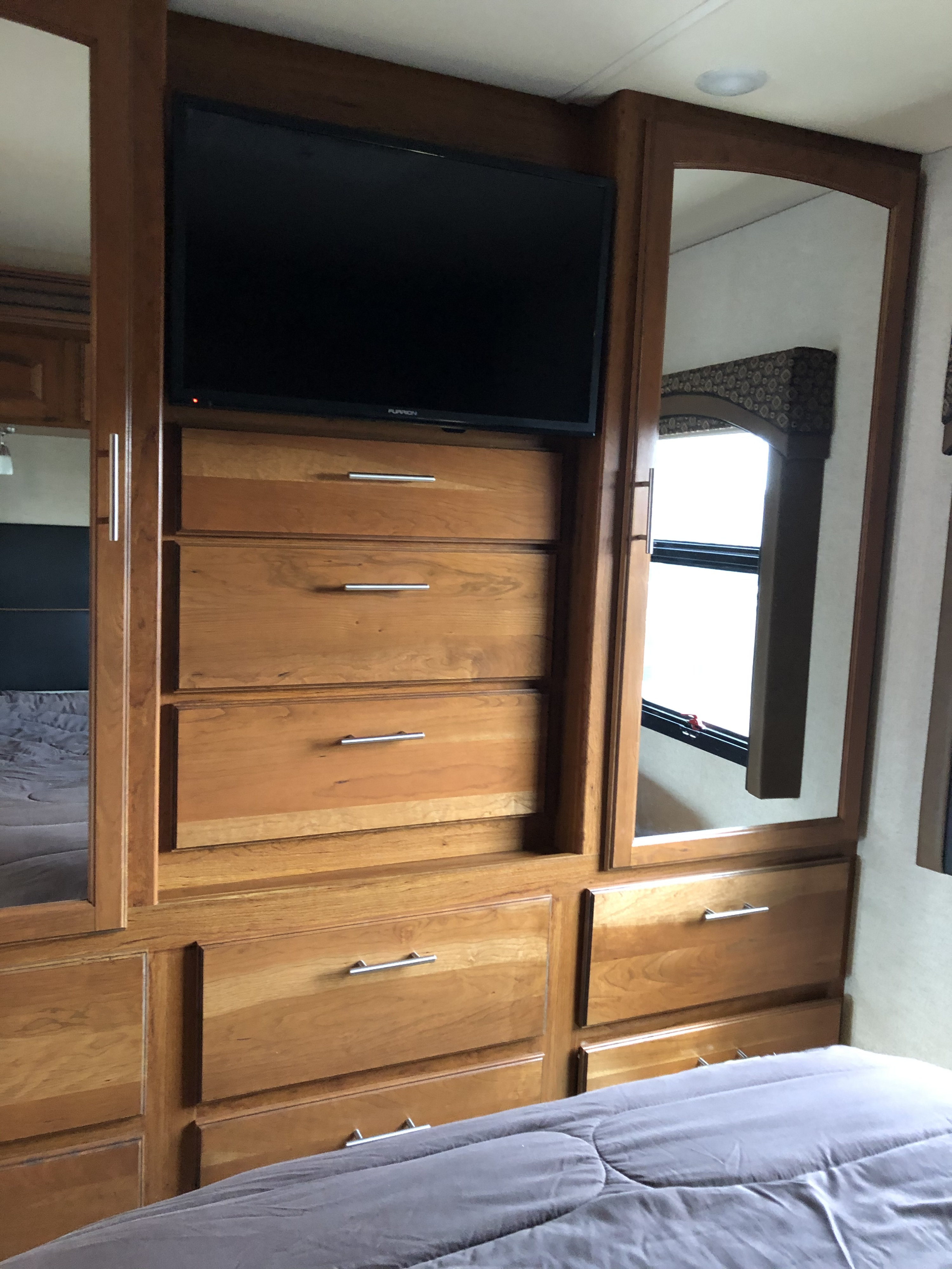Explore this rv rental bedroom: a built-in TV, wood dresser drawers, mirrored closets, and a comfortable bed.. Jayco Precept 2018