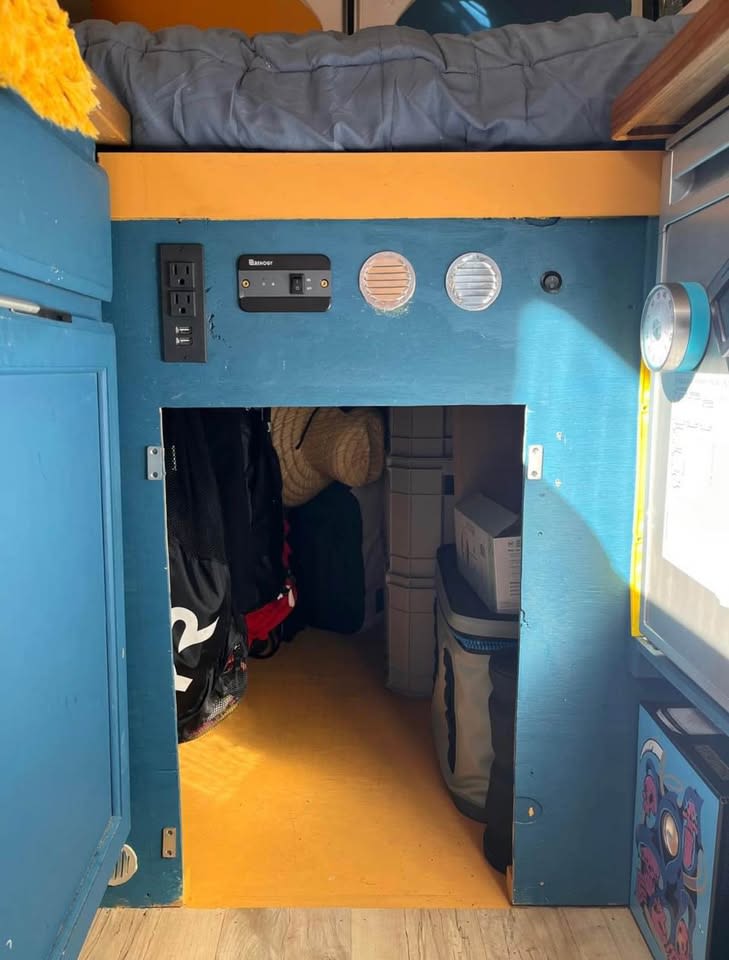 RV rental interior: Bed over a compact storage space with electrical outlets, Renogy controller, and vents. Yellow floor.. Dodge Ram 1500 2020