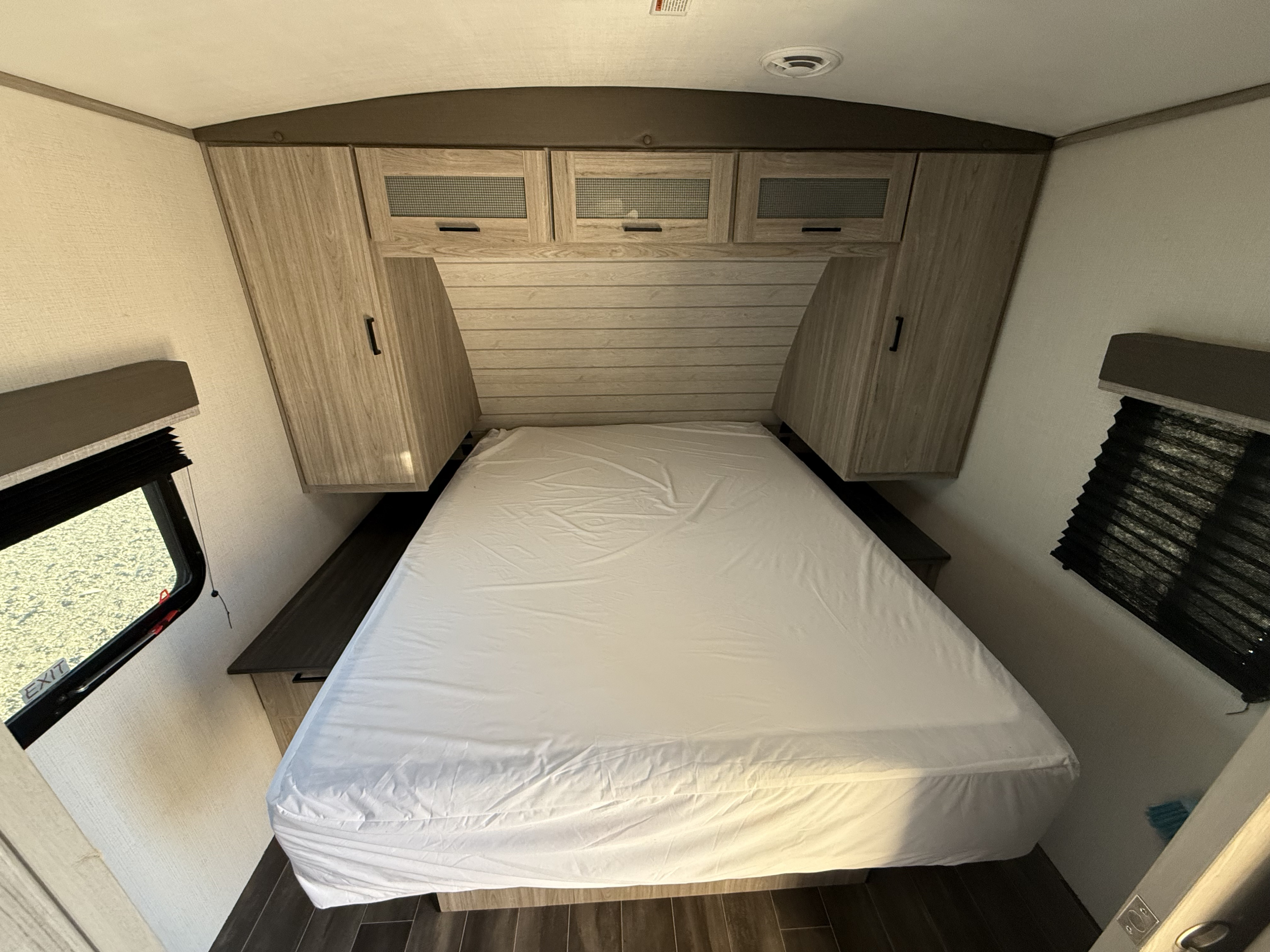 RV rental bedroom with bed, overhead cabinets, window blinds, and wood-look decor for comfortable travels.. Keystone RV Passport GT 2022