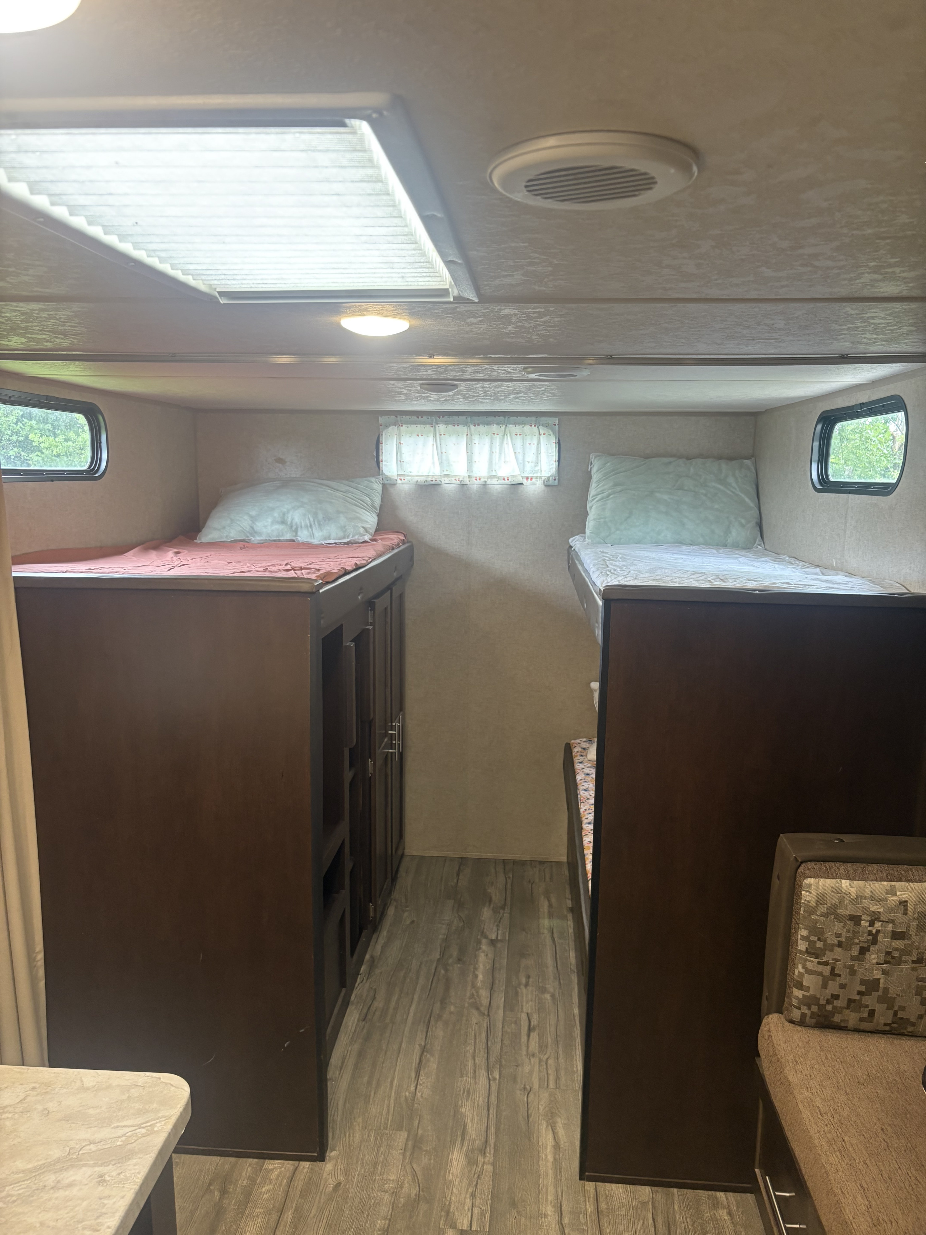RV rental interior: A spacious sleeping area with bunk beds, central aisle, windows, built-in storage, and comfy pillows.. Forest River Cherokee Grey Wolf 2018