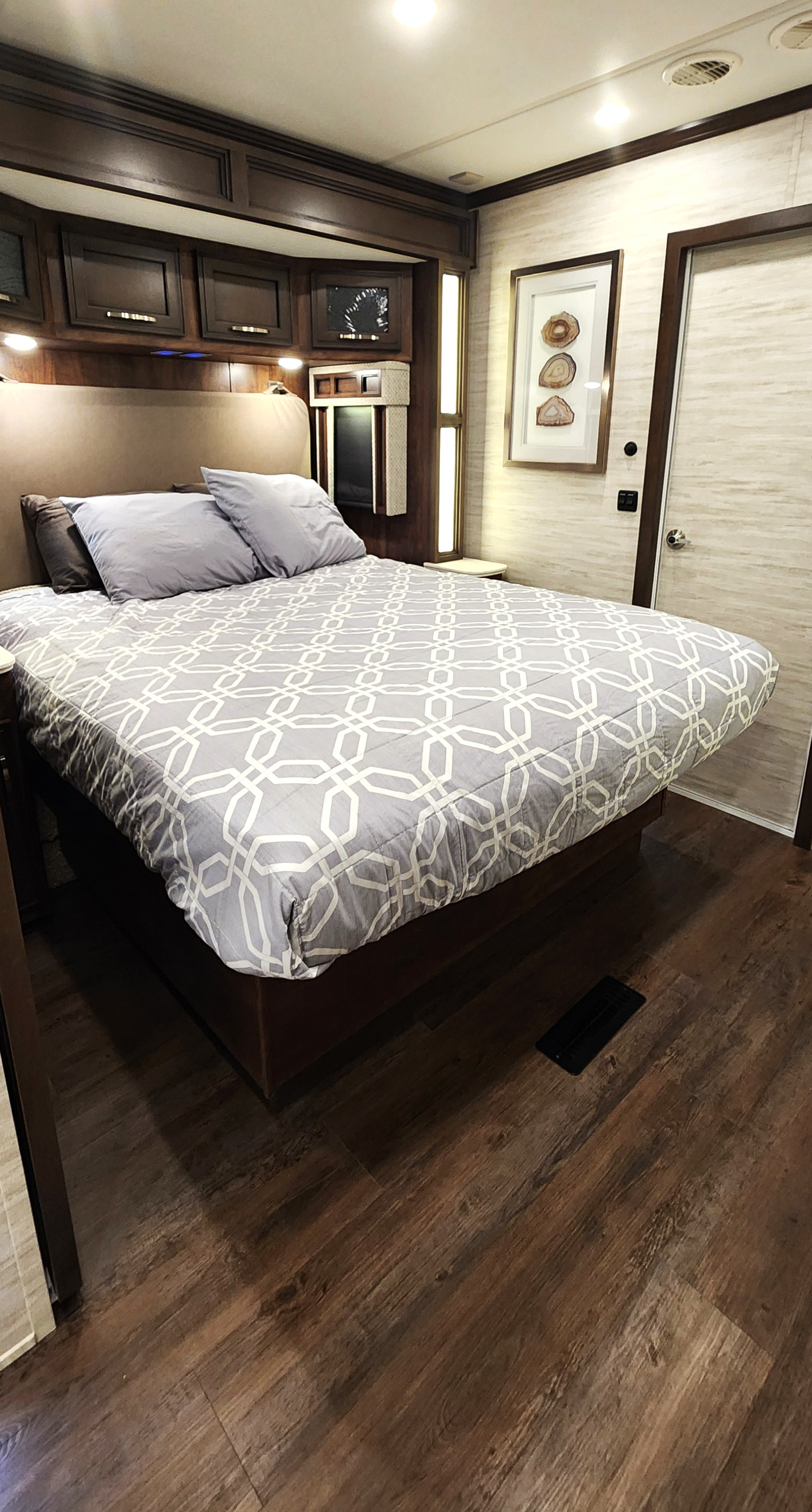 Modern RV rental bedroom interior featuring a large bed, dark wood cabinetry, and sleek decor, ideal for journeys.. Newmar Canyon Star 2024