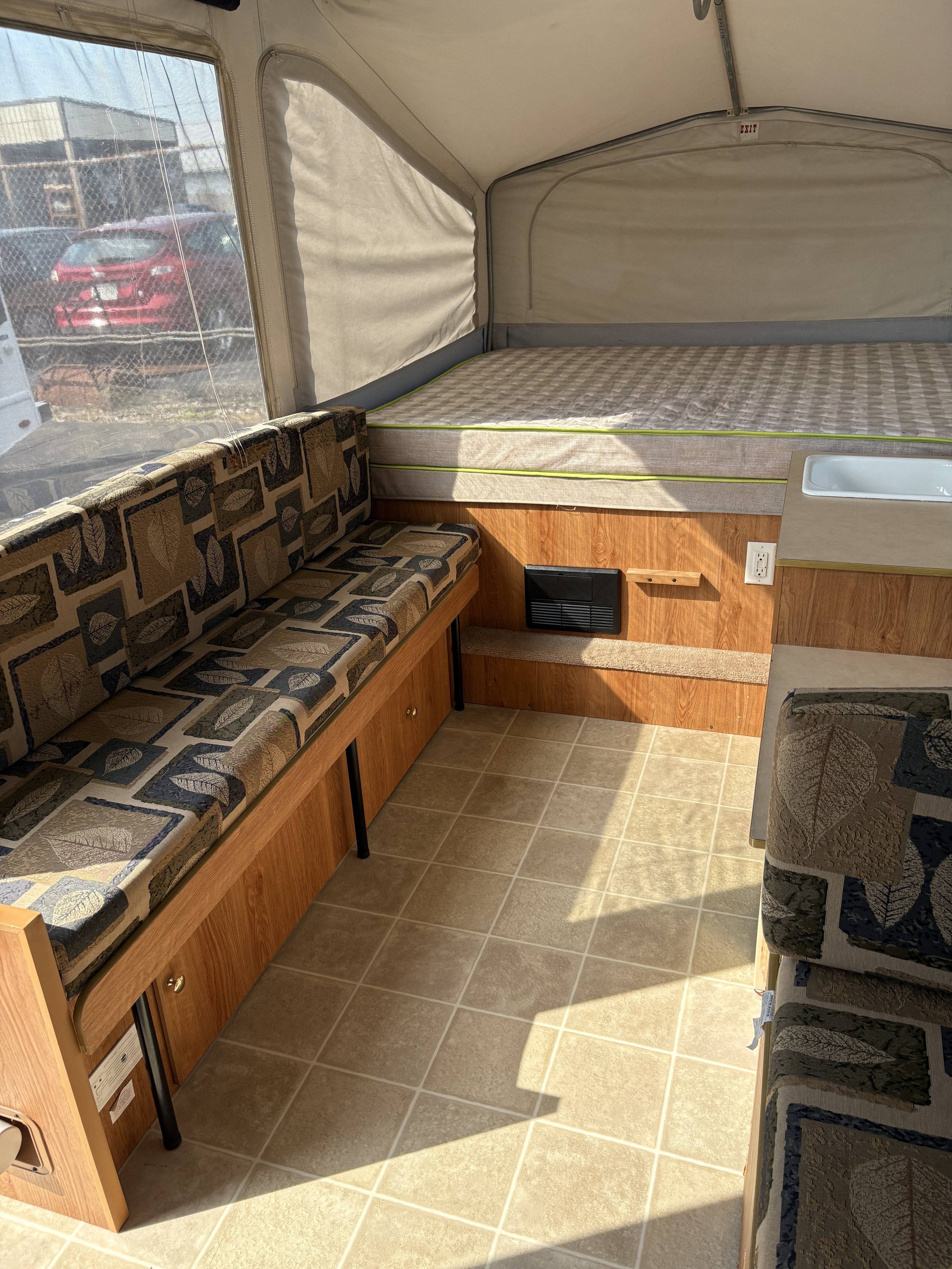 Inside an RV rental: a cozy pop-up camper with a comfy bed, patterned dinette, and bright interior living space.. Jayco Jay Series 2006