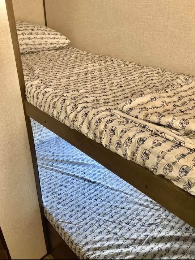 Cozy bunk beds with camper van patterned sheets inside an RV rental. Ideal sleeping arrangements for travel adventures.. Dutchmen Coleman Lantern LT 2021