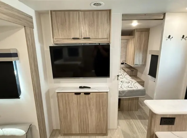 Discover a modern RV rental interior featuring a TV entertainment center, wood cabinets, and bedroom access.. Winnebago Access AC30BH 2023