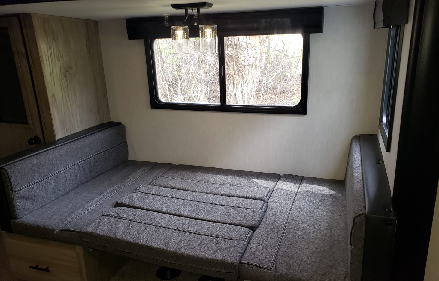 RV rental: Bright interior with a convertible dinette/bed, window framing trees, and modern ceiling light.. Forest River Cherokee Alpha Wolf 2022