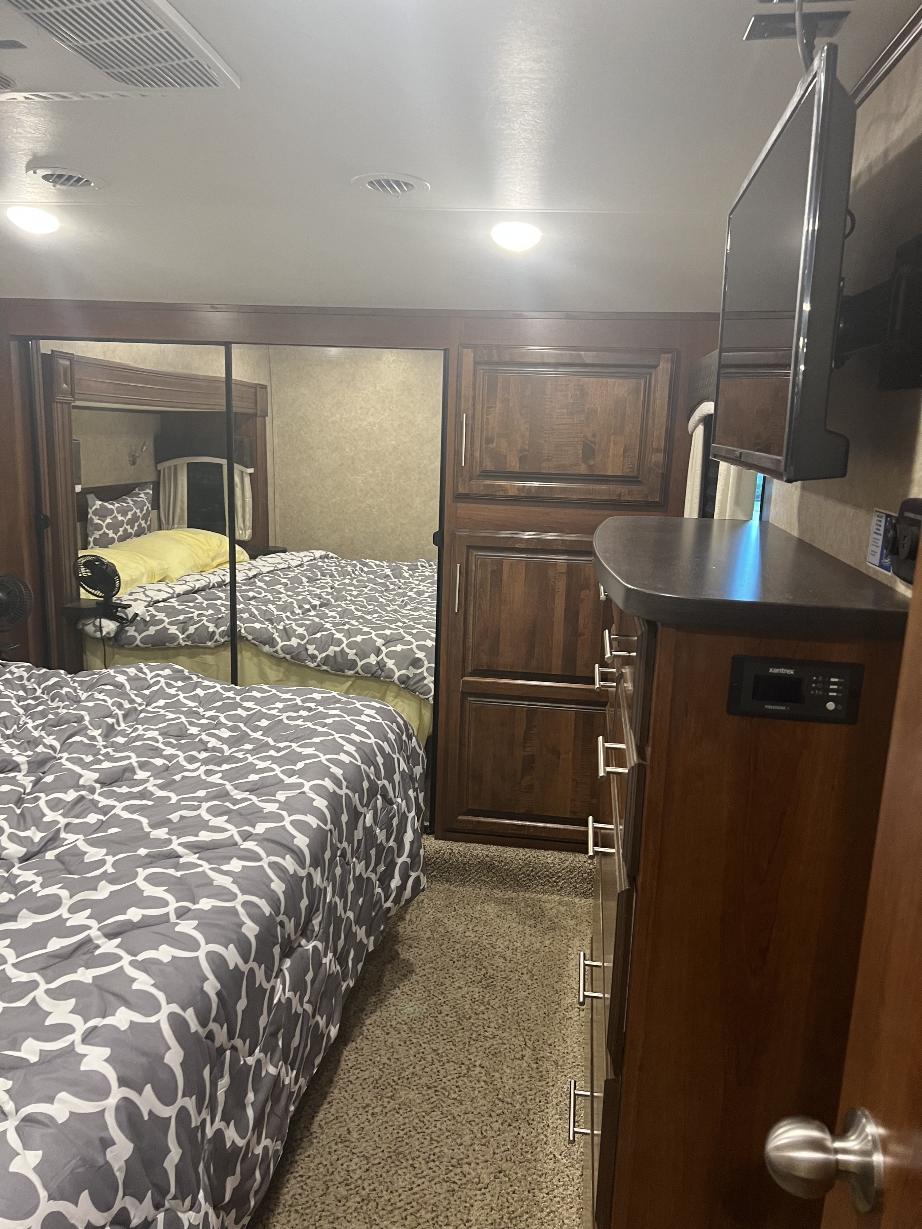 This RV rental bedroom features two beds, wood cabinets, a TV, and Xantrex controls. Ideal for travel.. Jayco Eagle 2018