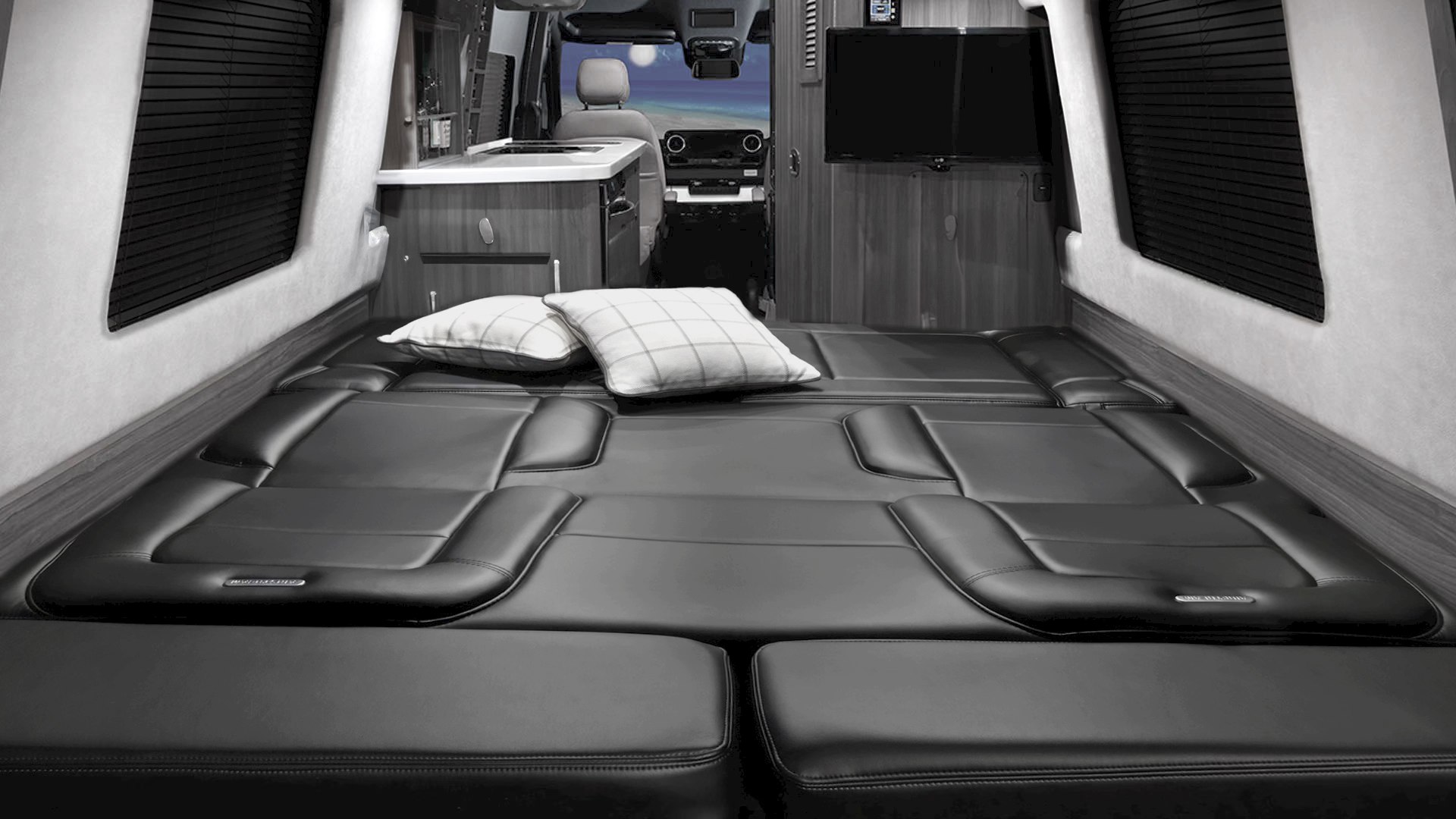 Spacious RV rental interior with a large black leather bed, kitchenette, and TV. Ideal for road trips.. Airstream Interstate 2016