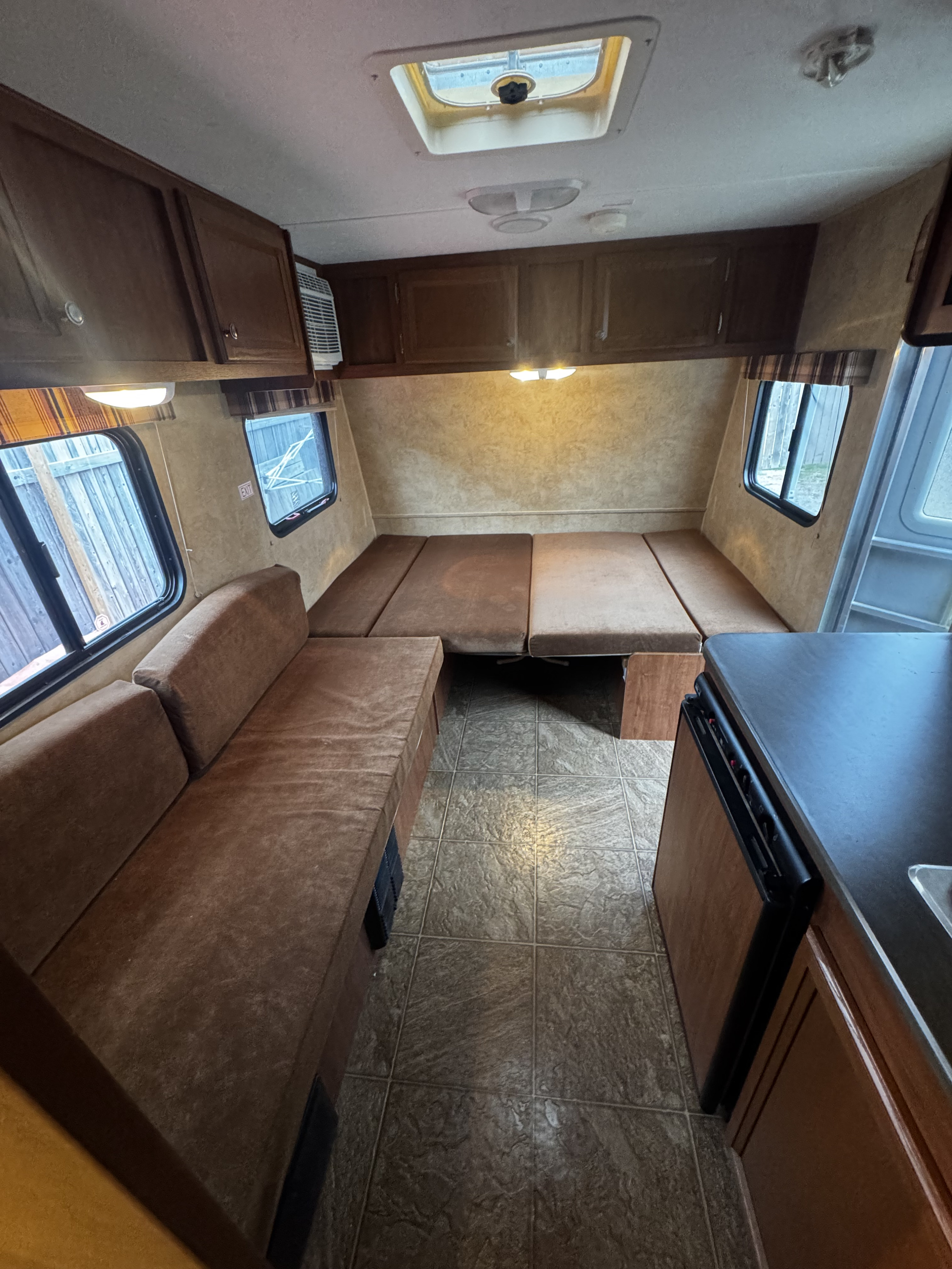 Inside an RV rental: a versatile living area with U-shaped couch/bed, compact kitchen, overhead storage, & skylight.. Jayco Jay Flight Swift SLX 2012