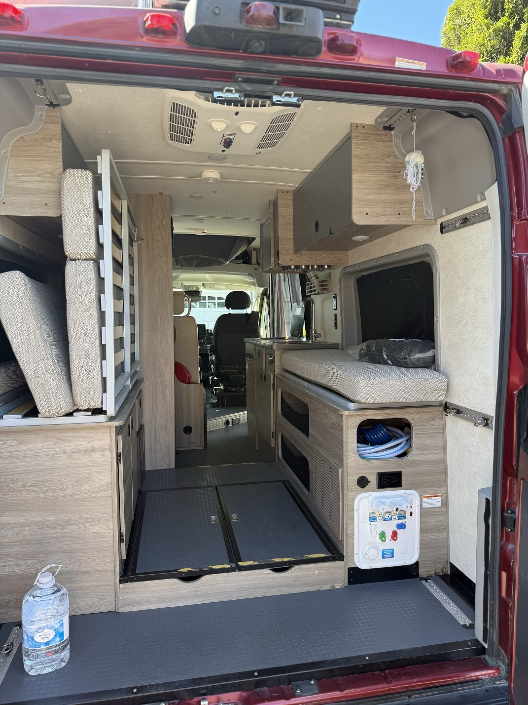 This RV rental interior, viewed from the rear, features a convertible bed, kitchen area, and storage solutions for travel.. Winnebago Solis 2021