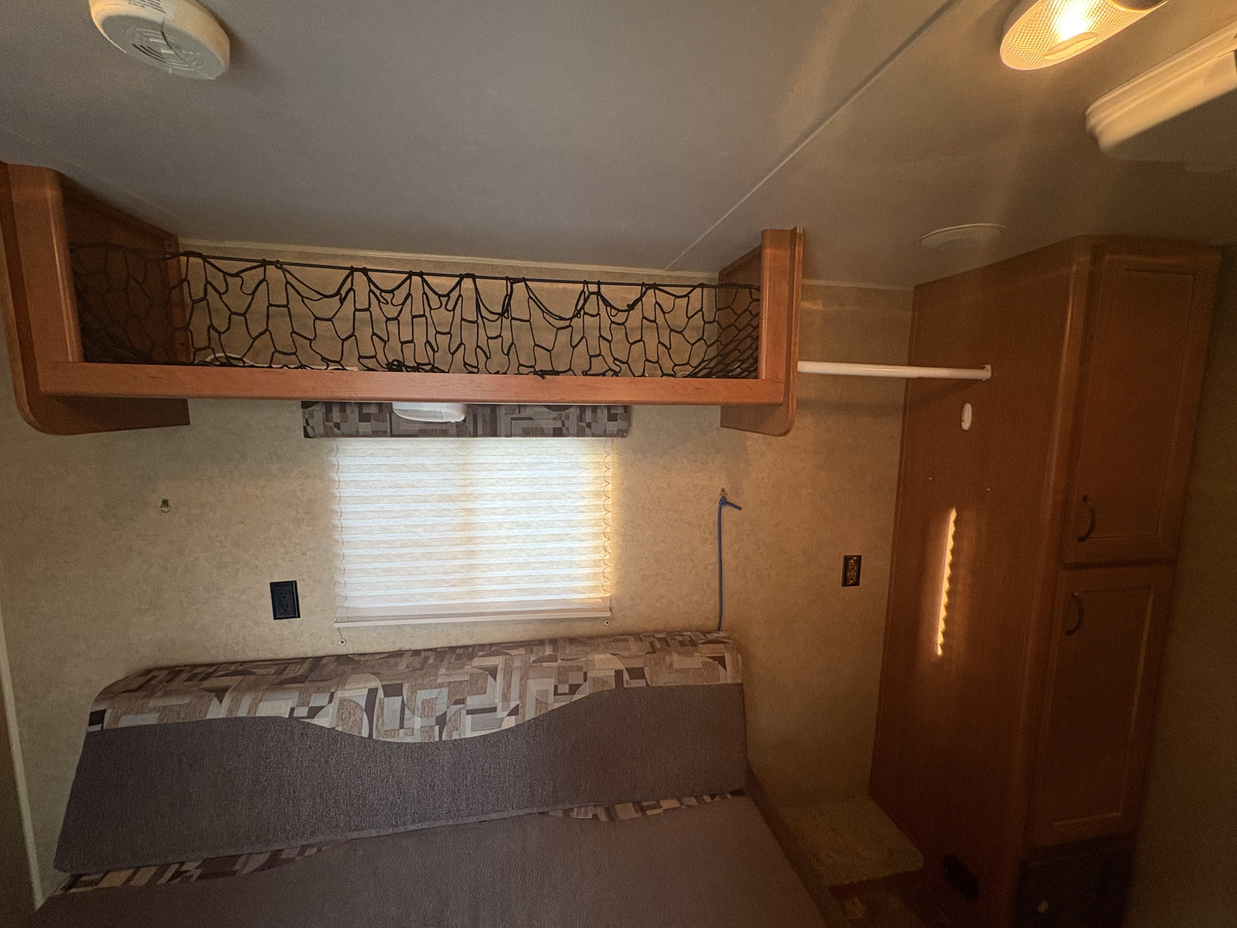 Cozy RV rental interior featuring a bunk bed with safety net, window, and cabinet. Perfect for your next adventure!. Forest River Cherokee Grey Wolf Toy Hauler 2014