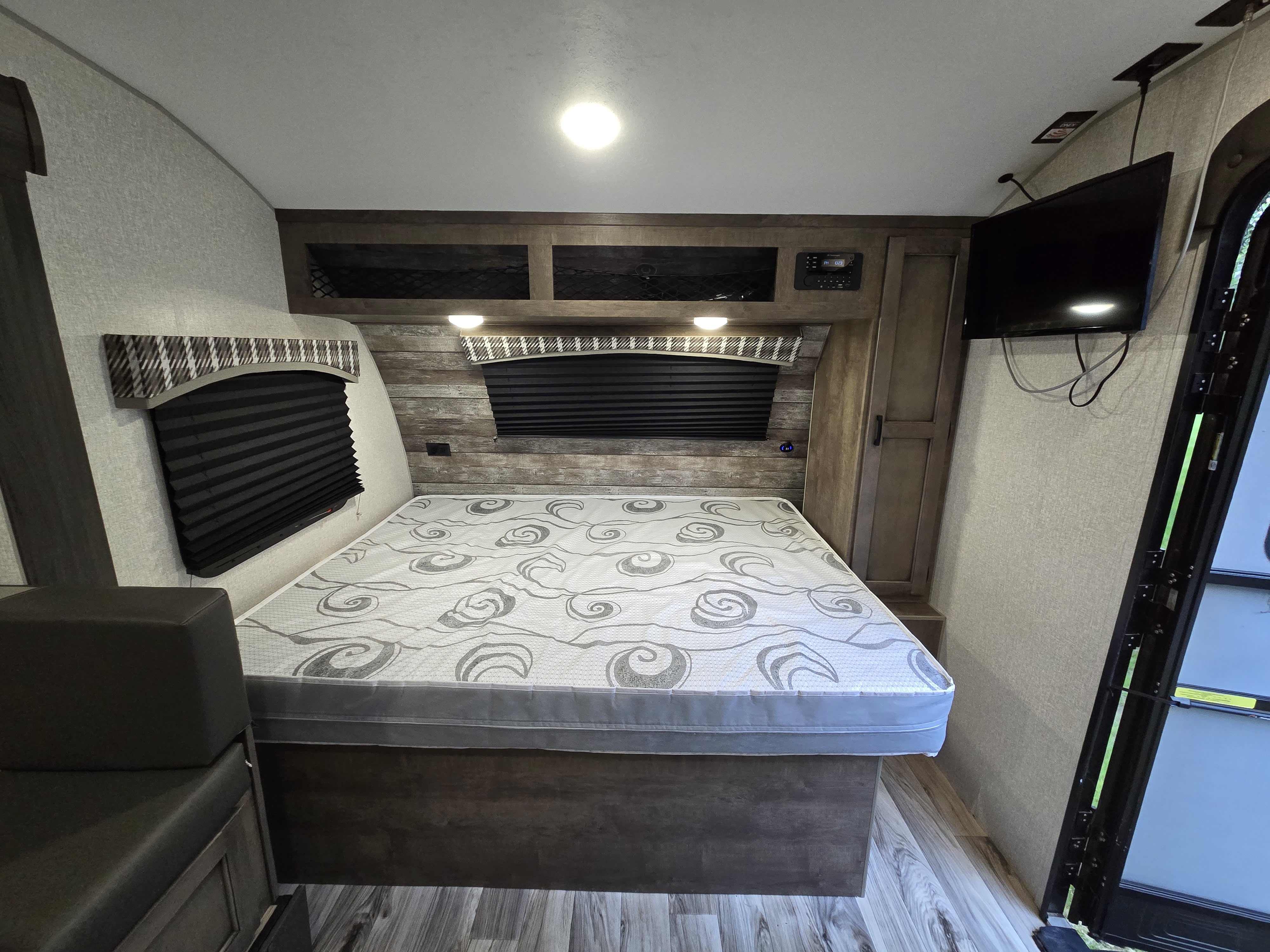 Cozy RV rental bedroom: Features a patterned bed, storage, TV, and seating. Perfect for comfortable travels.. Sonic Lite 2022
