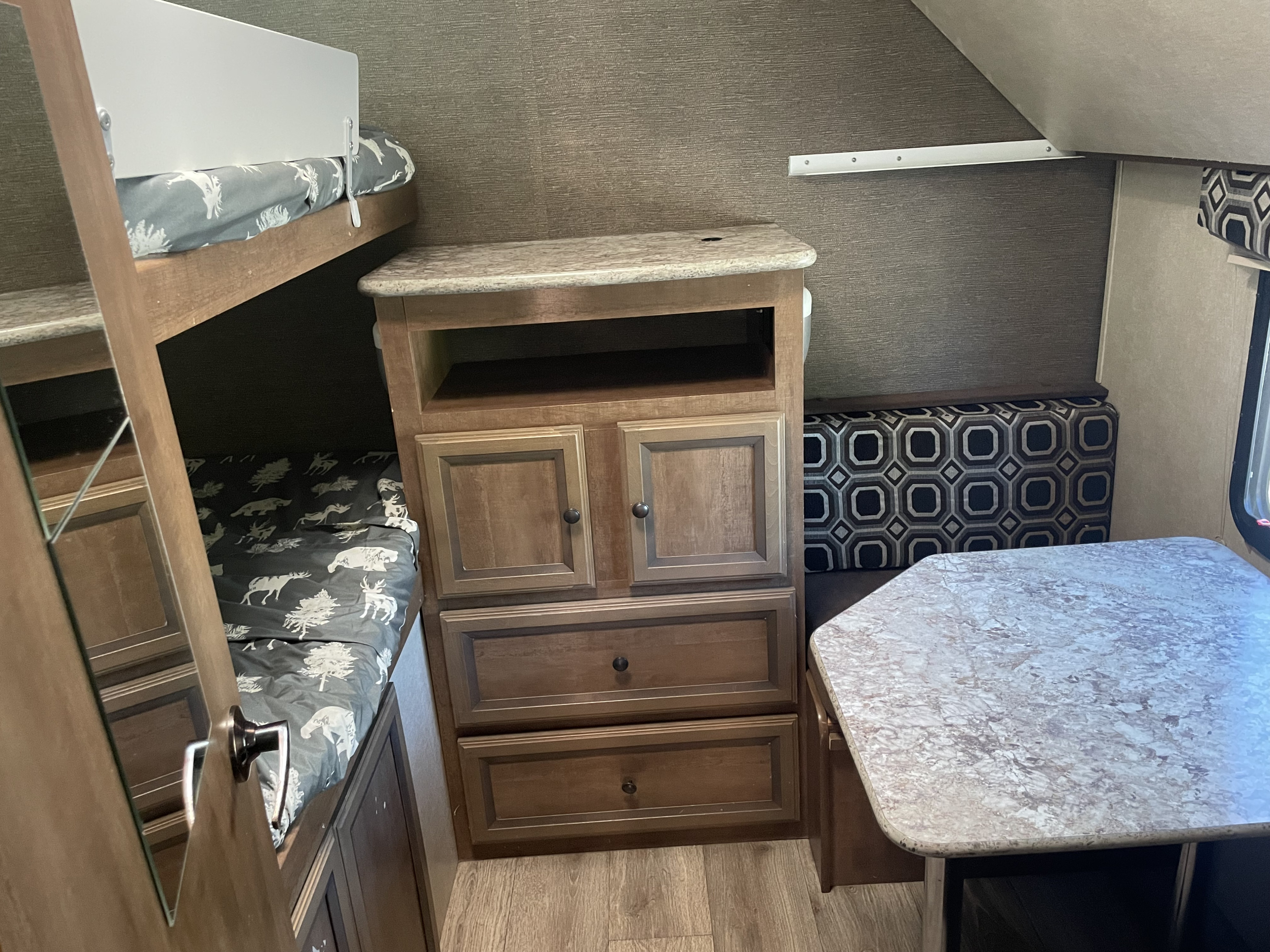 Cozy rv rental interior featuring bunk beds with animal bedding, central storage, and a dinette with patterned cushions.. Cruiser RV Radiance 2015