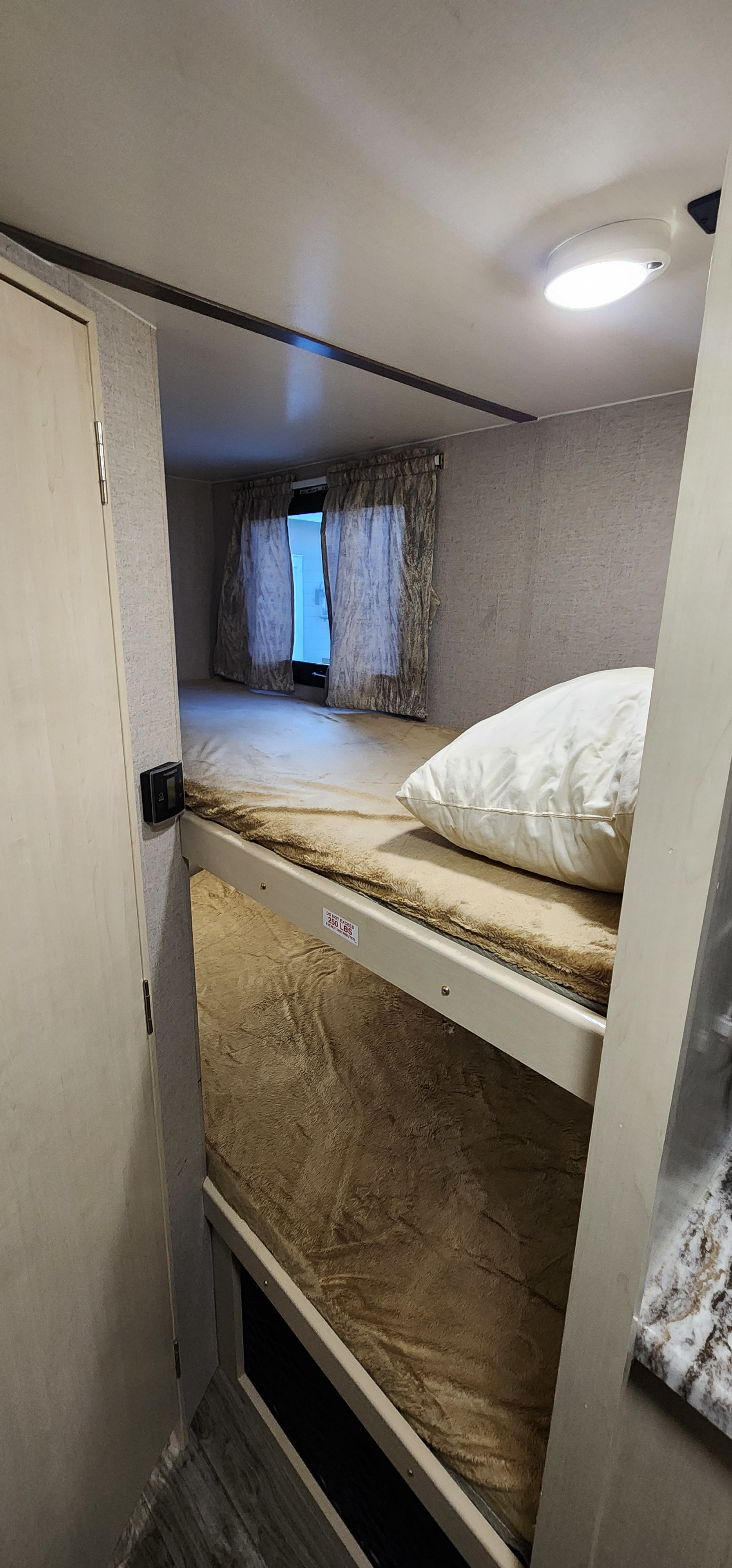 RV rental interior featuring cozy bunk beds with plush blankets and a pillow, offering a comfortable travel trailer sleeping area.. Minnie Micro Minnie 2019