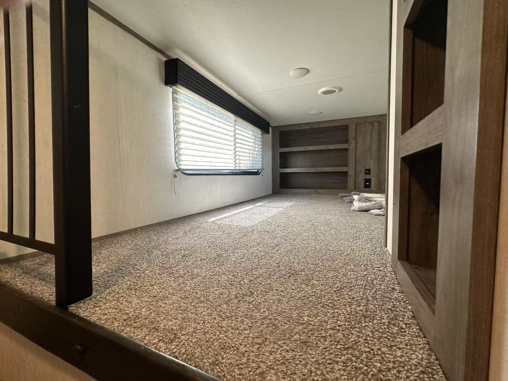 RV rental's carpeted bunk loft with a wide window, built-in shelves, and a metal railing.. Forest River Sabre 2021