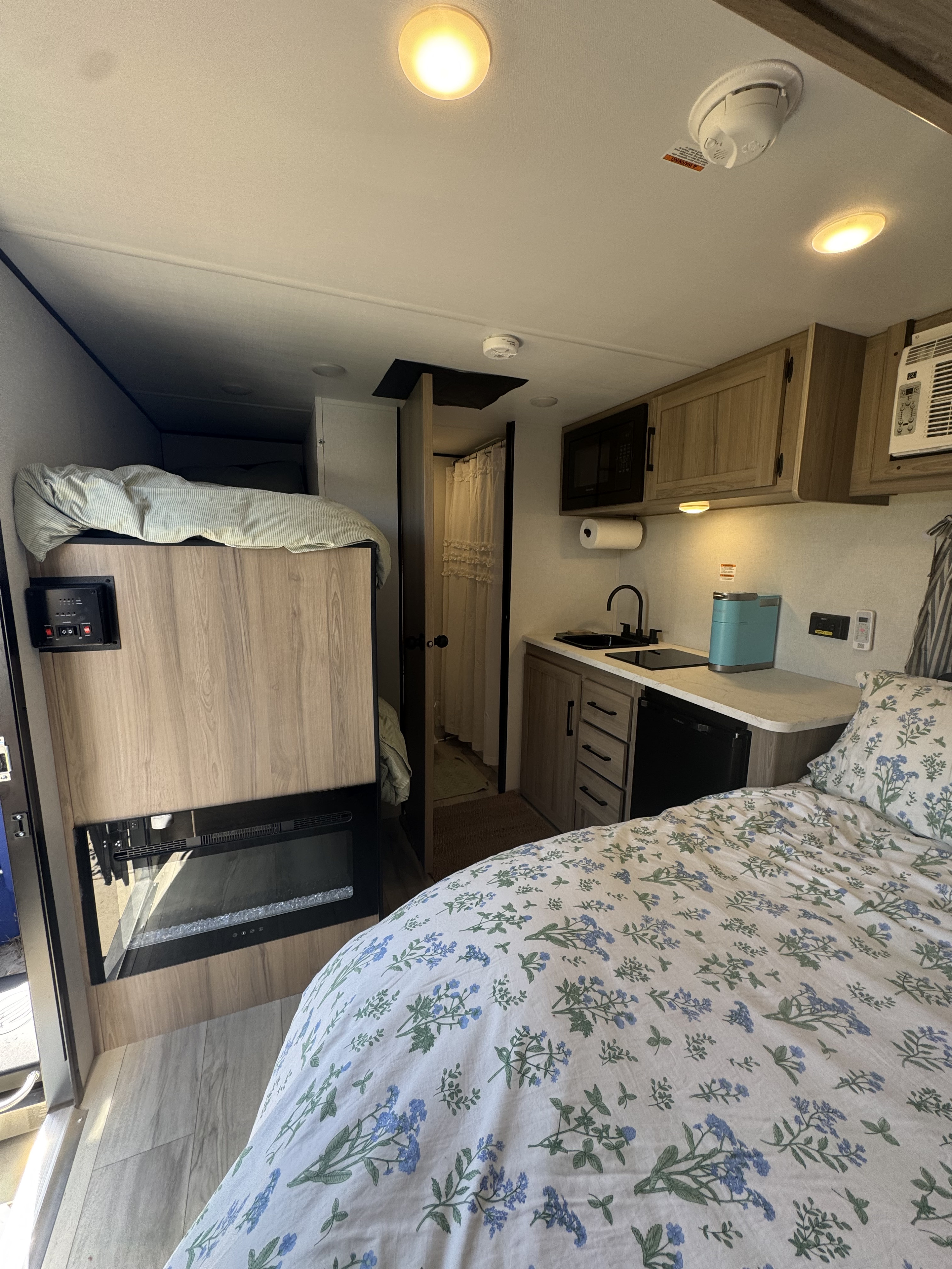 Cozy RV rental interior featuring a main bed, bunk bed, fireplace, and modern kitchen. Ideal for comfortable travel.. Keystone Coleman 13b 2025