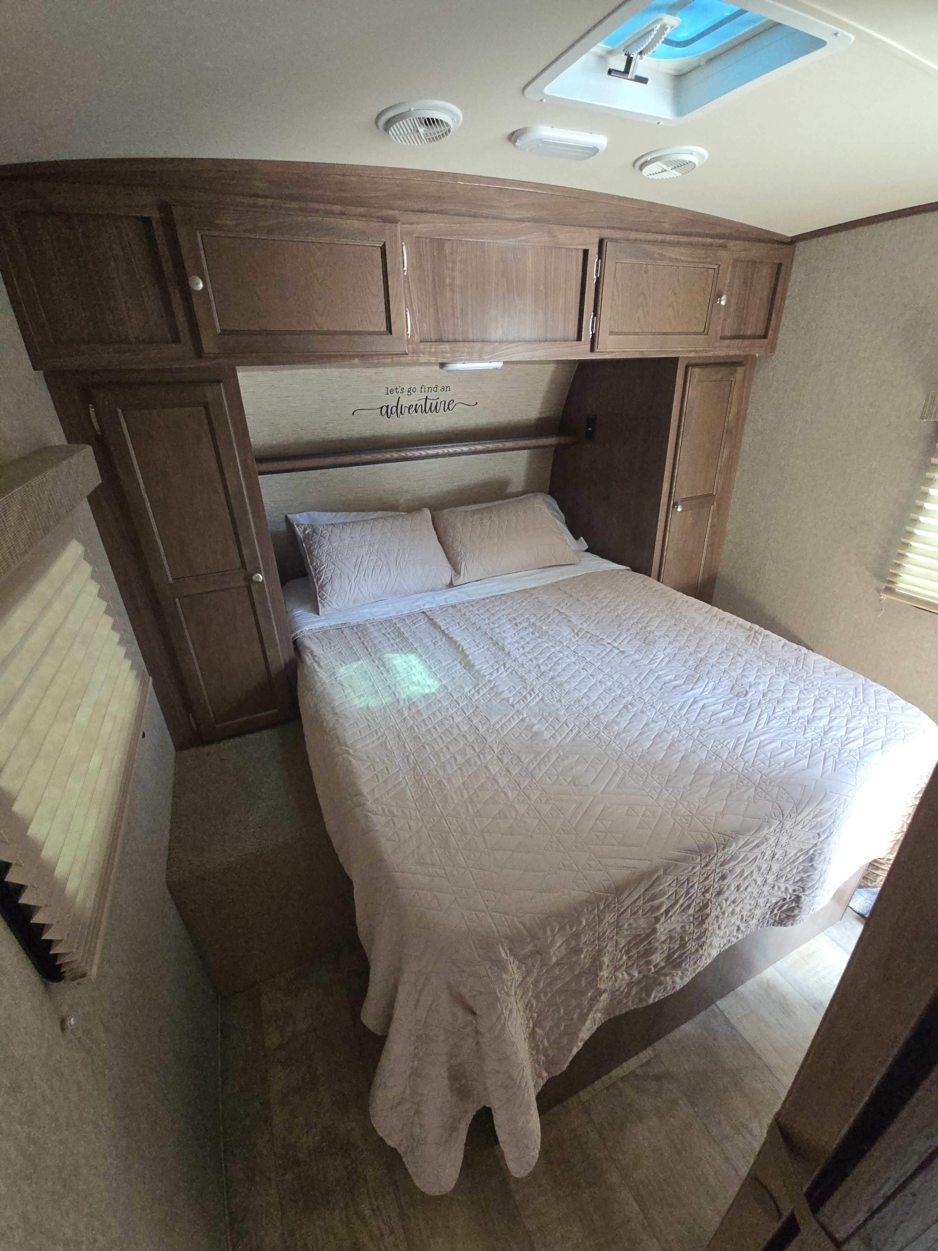 RV rental: Cozy bedroom with a bed, quilted bedding, wooden cabinets, and an "adventure" wall decal.. Palomino Solaire 2015