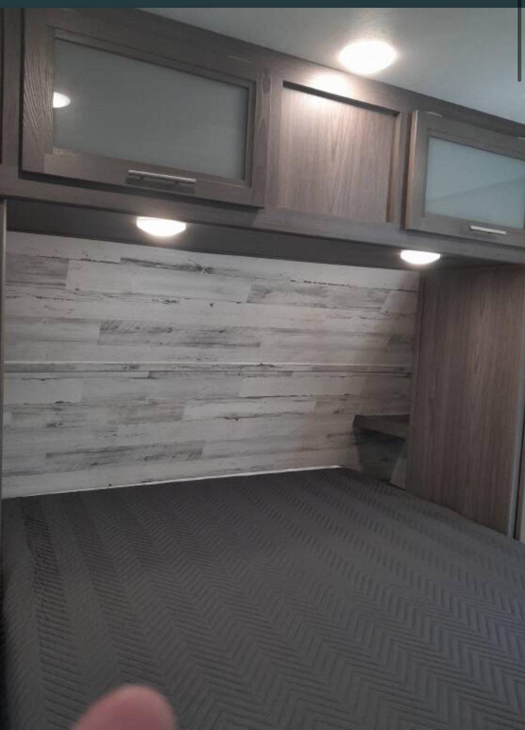 RV rental: Modern bedroom featuring wood cabinets, under-cabinet lighting, a distressed wood accent wall, and comfy bed.. Dutchmen Kodiak Ultra Lite 2023