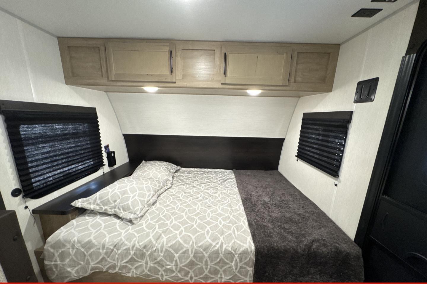 RV rental bedroom featuring a large bed, overhead storage, and dual windows with blinds.. Forest River Inc flagstaff 823D camper trailer 2026