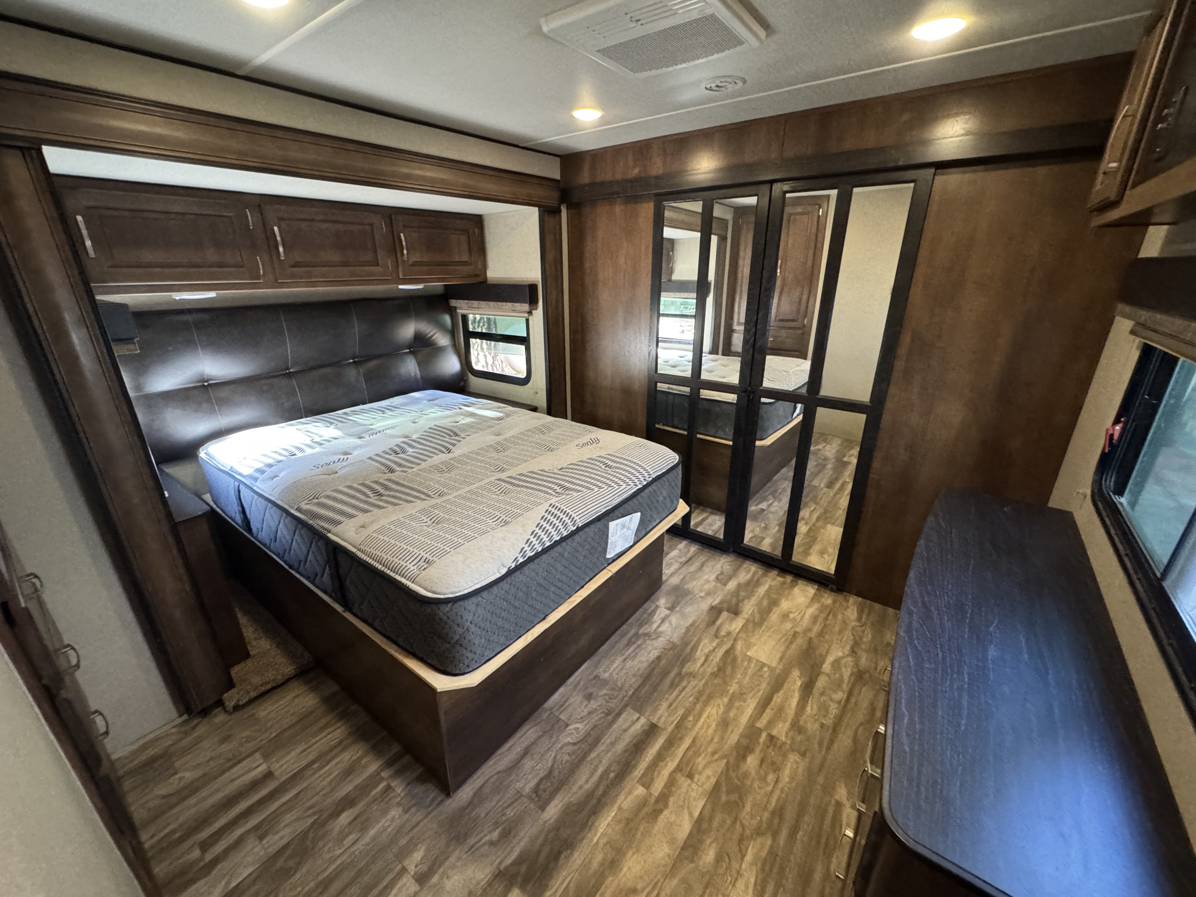 This rv rental offers a spacious bedroom with a Sealy mattress, wooden cabinets, mirrored closet, and a dresser. Enjoy comfortable travel.. Grand Design Reflection 2018