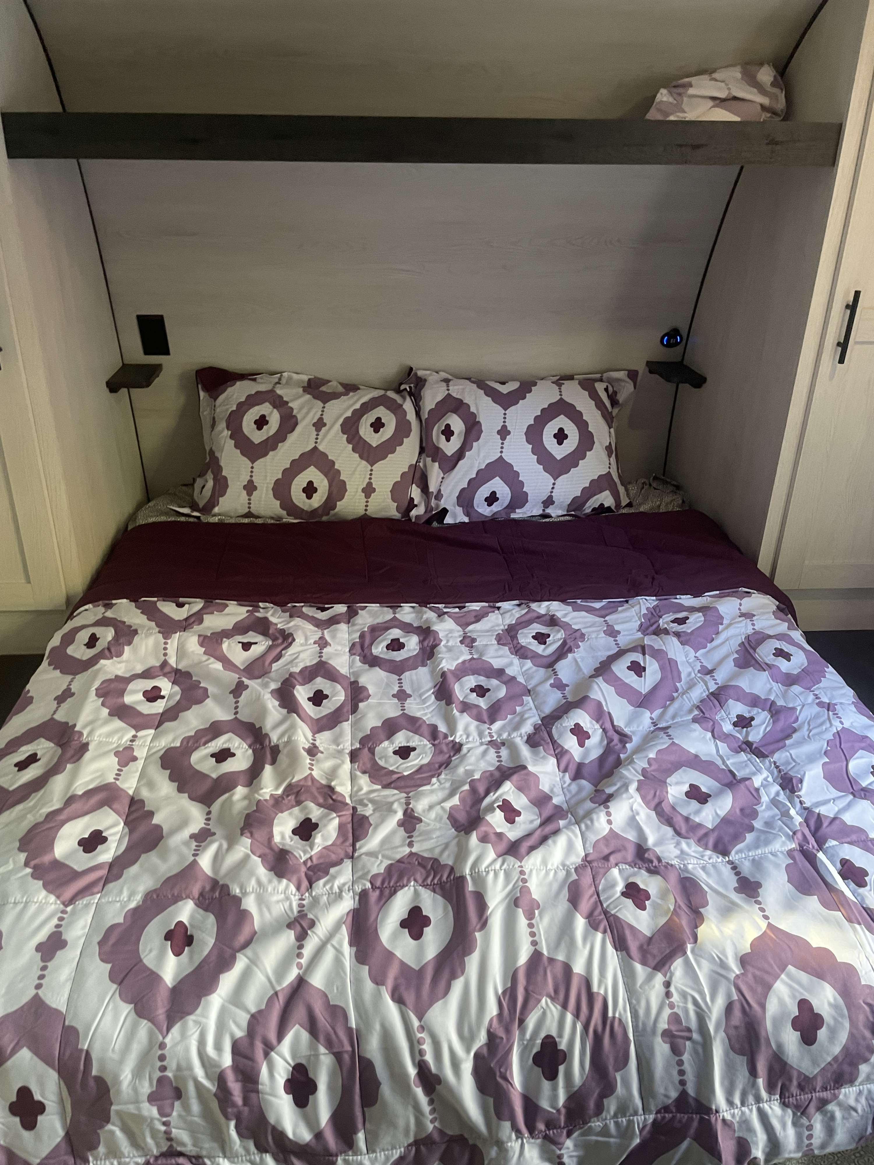 Cozy RV rental bedroom with purple patterned bedding and built-in storage. Ideal for travel comfort.. KZ sportsman bh281 2022