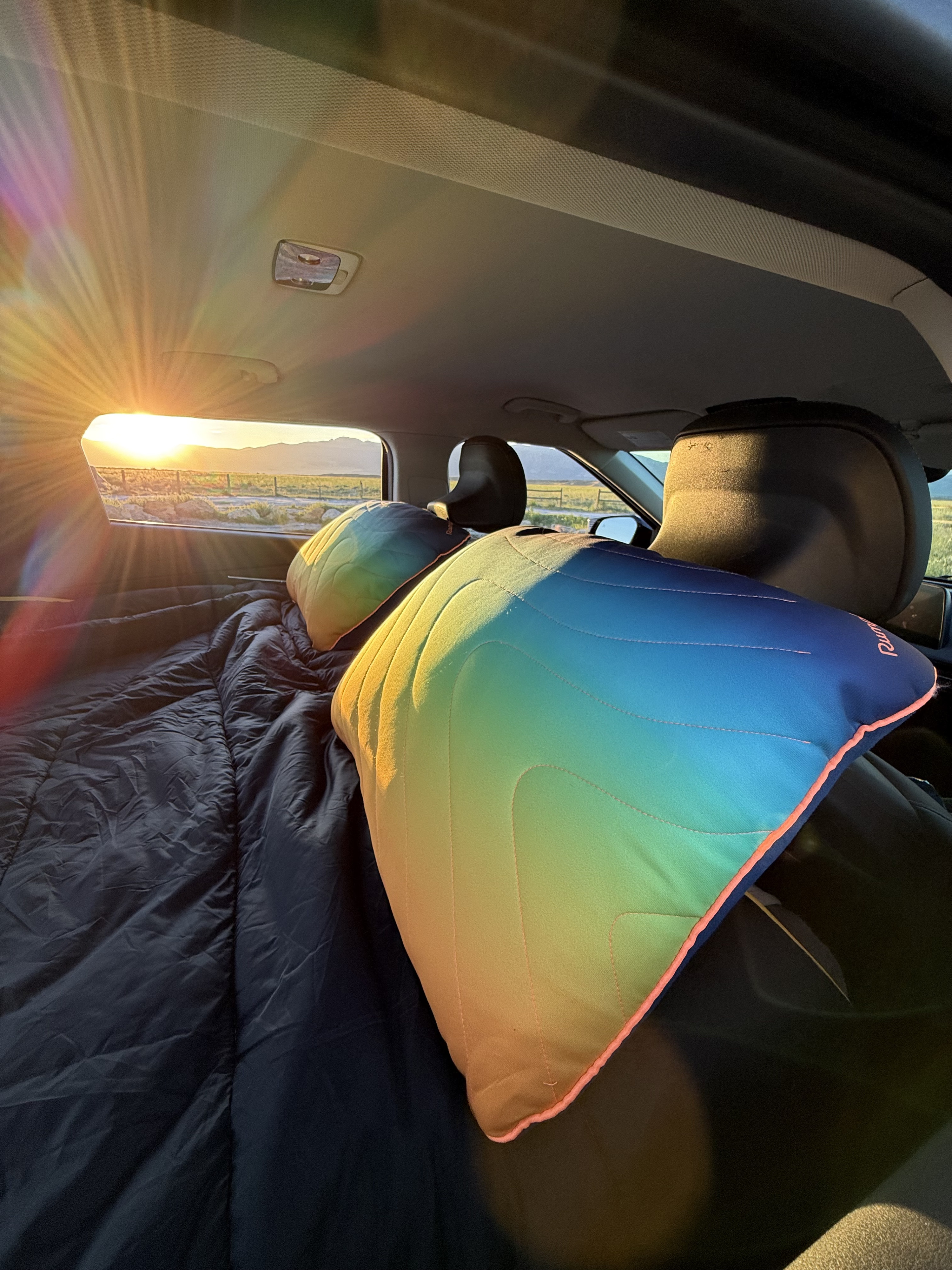 Cozy car camping setup with sunset views through the back window, perfect for your next road trip or rv rental adventure.. Kia EV6 Wind All Wheel Drive 2022