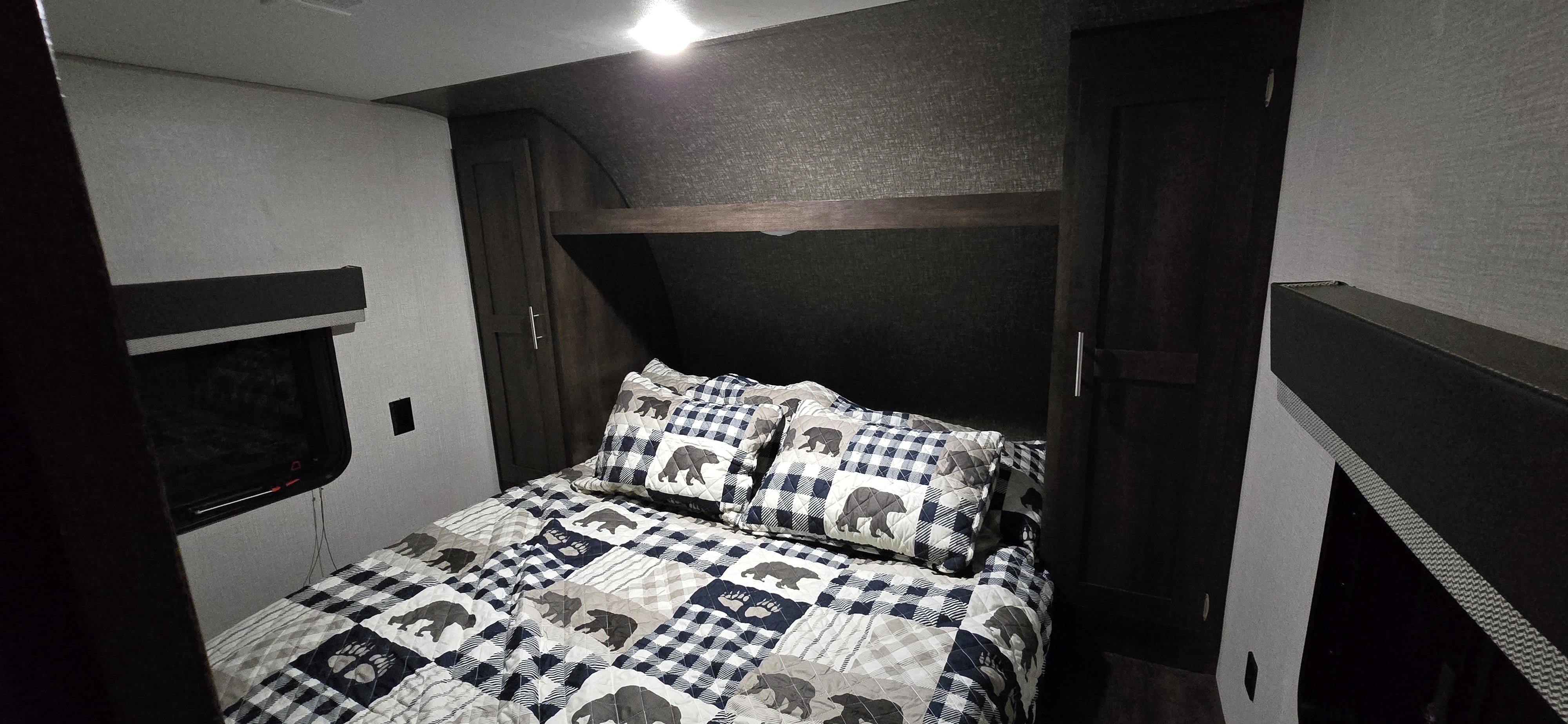 Cozy RV rental bedroom featuring a bear-themed bed, built-in storage, and a wall-mounted TV for comfortable travels.. KZ 301BHKSE 2021