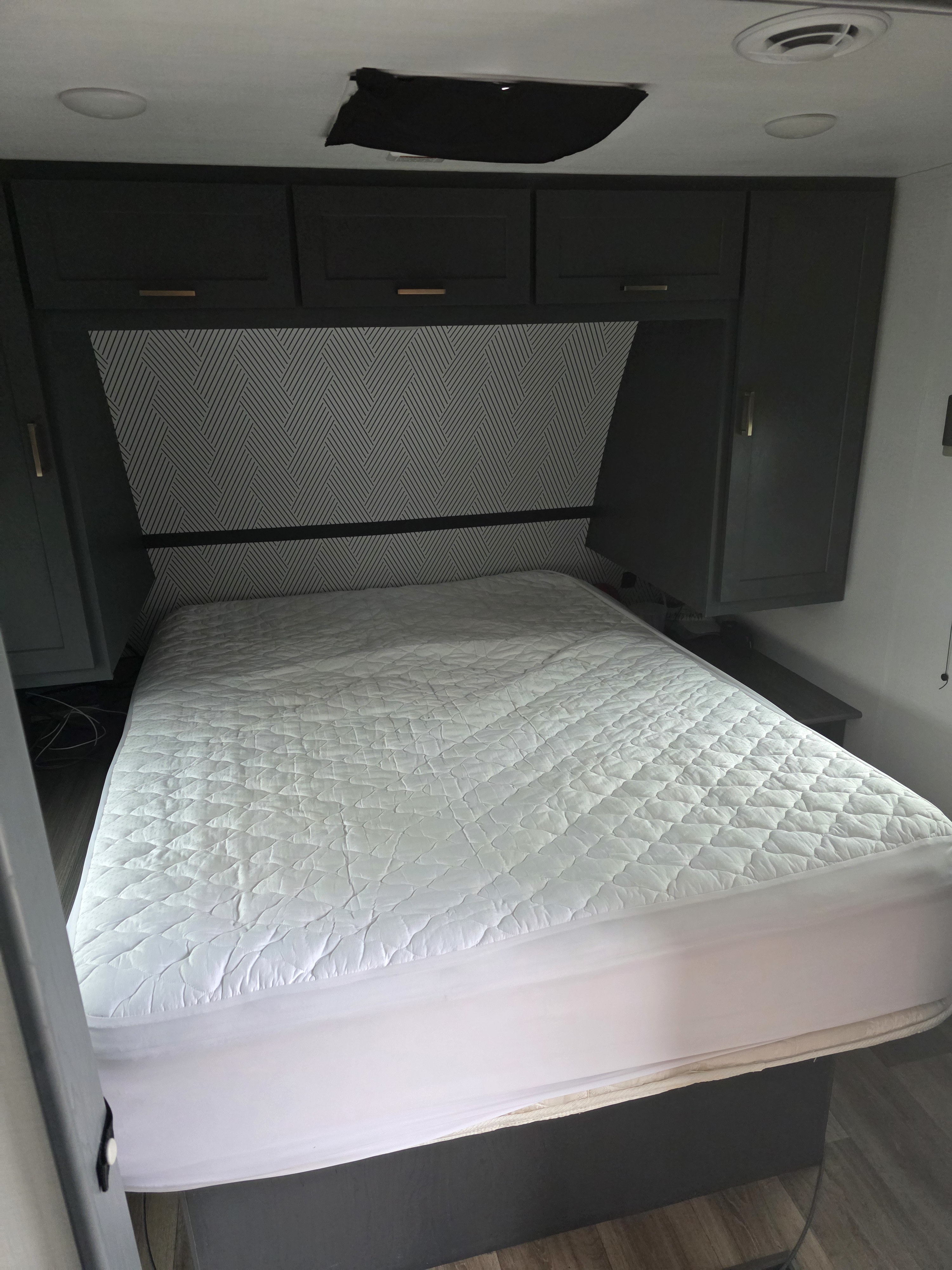 Modern RV rental bedroom featuring a comfy bed, stylish dark cabinets, geometric headboard, and ceiling AC/lighting.. Keystone RV Bullet Crossfire 2024