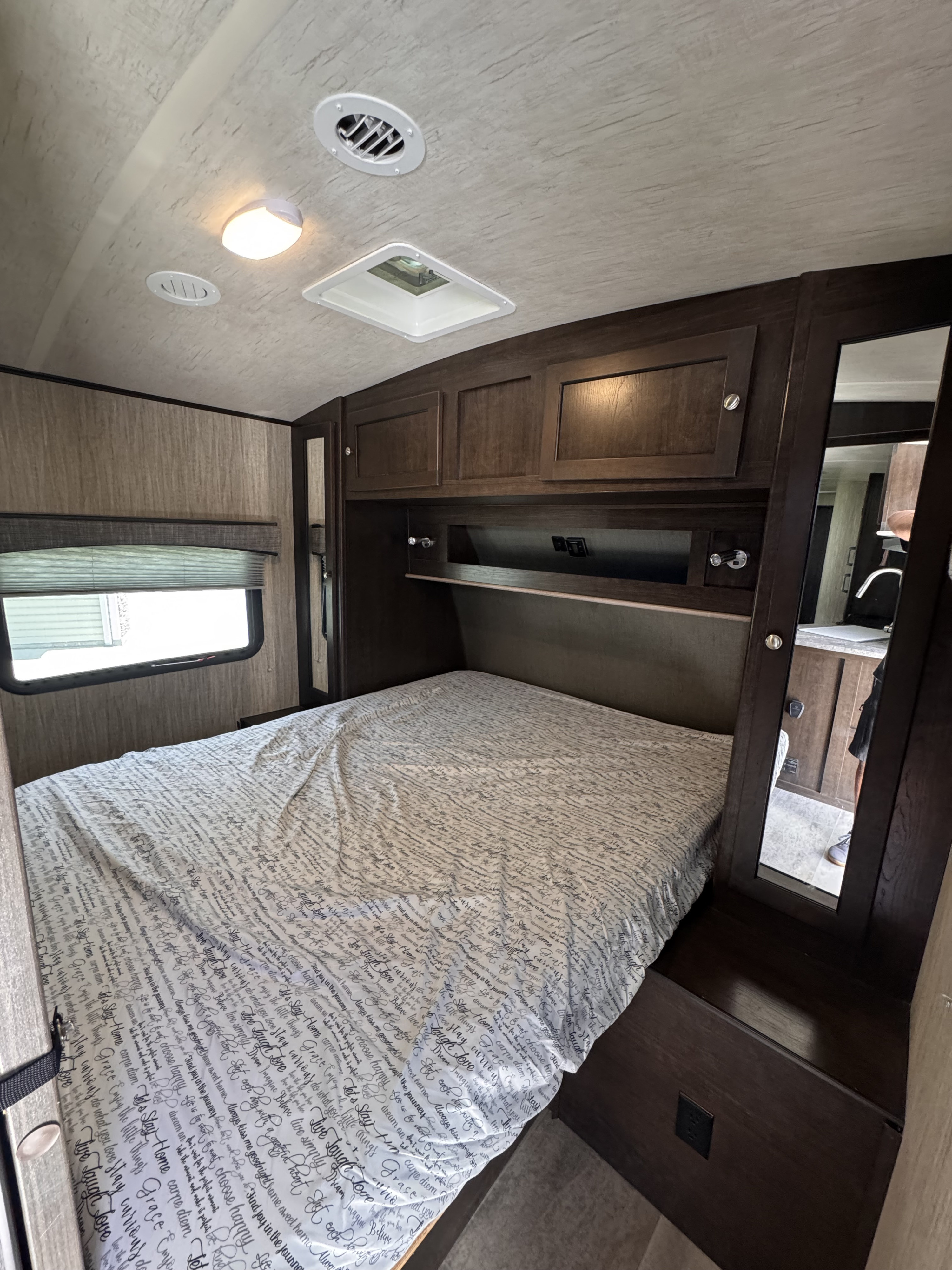 RV rental bedroom with bed, wood cabinets, window, ceiling vents & mirrored closet.. Heartland RVs Sundance 2019