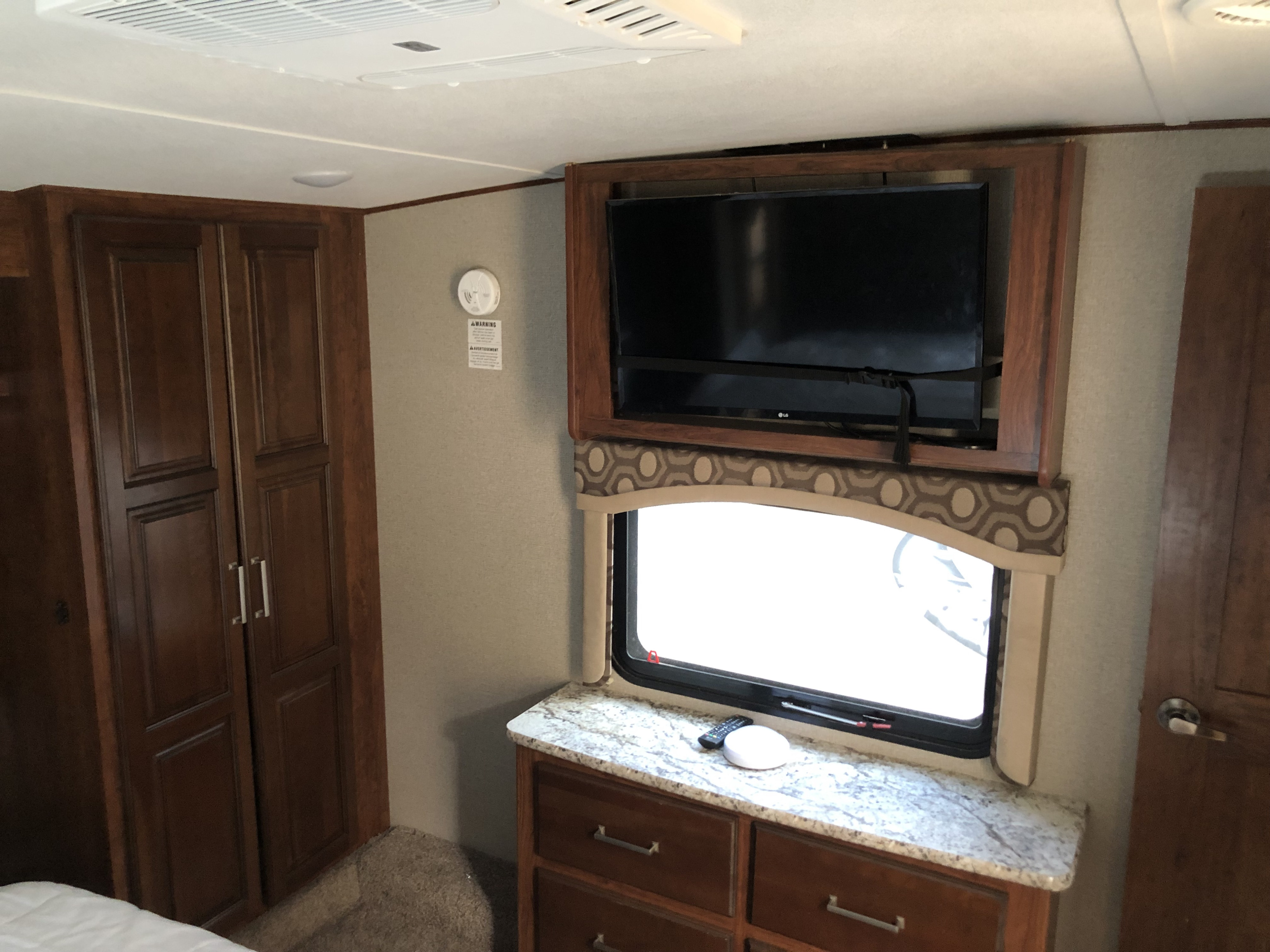 Comfortable RV rental interior: TV over window, dresser, and ample wardrobe storage. Ready for your road trip!. Keystone RV Avalanche 2017