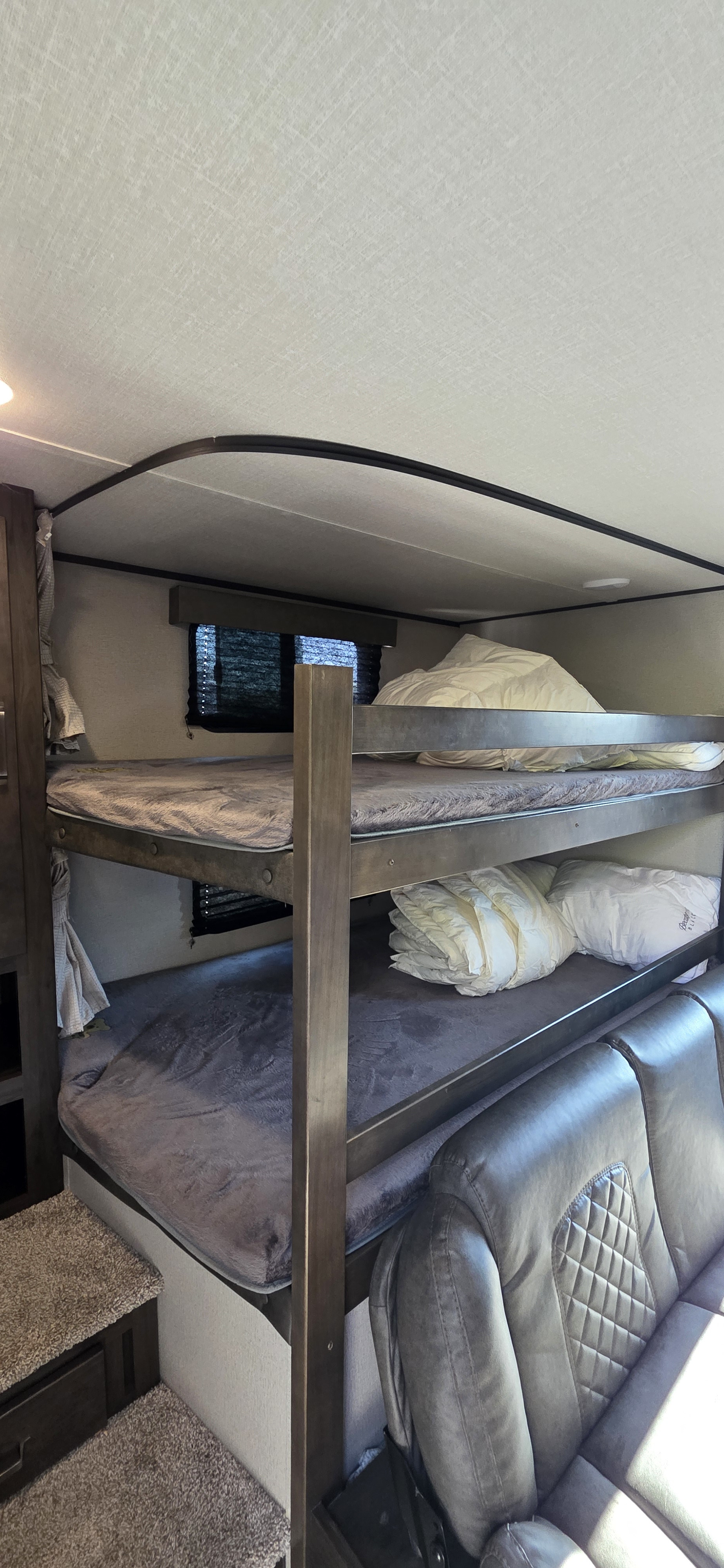 Cozy RV rental interior with bunk beds and a comfortable gray couch, perfect for family travel.. Grand Design Transcend Xplor 2021