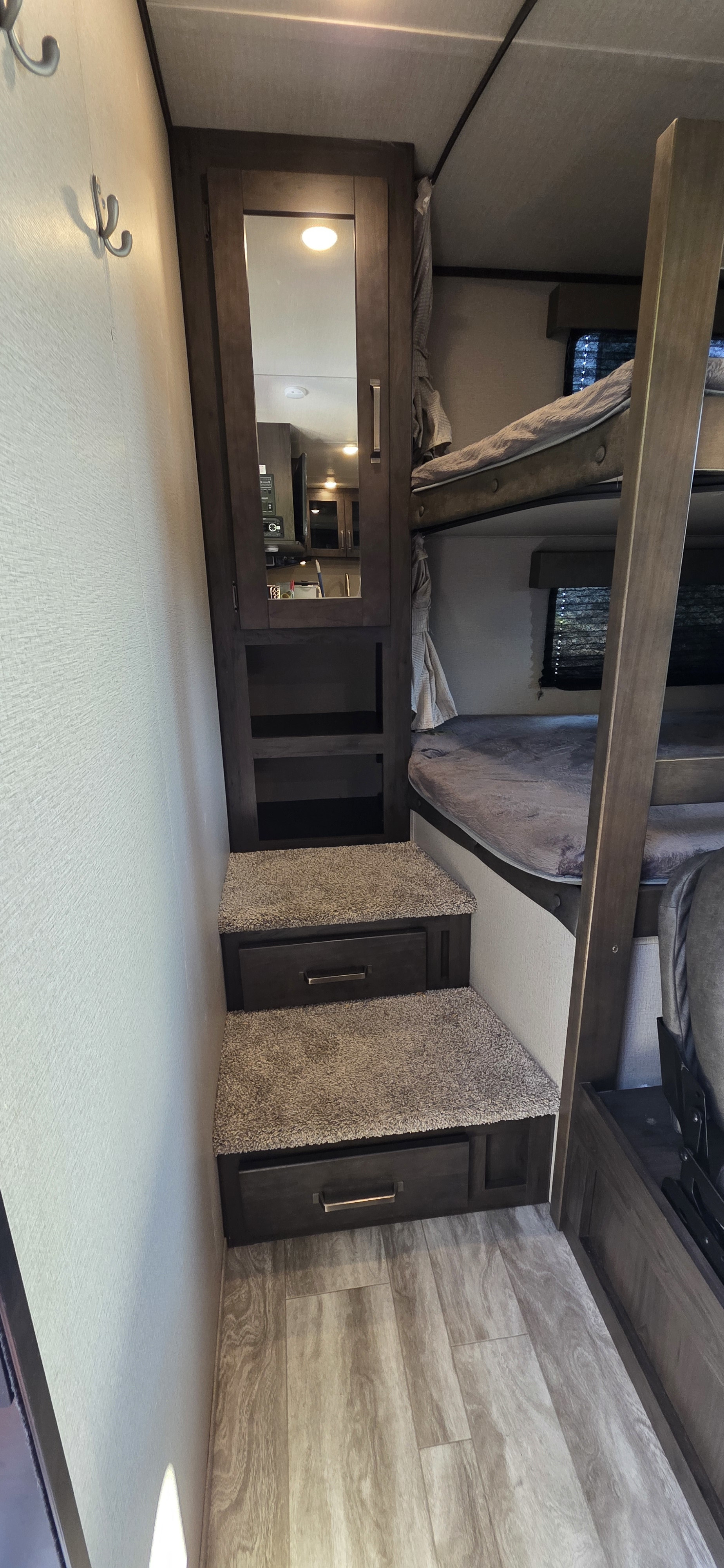 Efficient RV rental design: bunk beds, built-in storage stairs, and kitchen area reflected in a mirrored cabinet. Smart storage.. Grand Design Transcend Xplor 2021