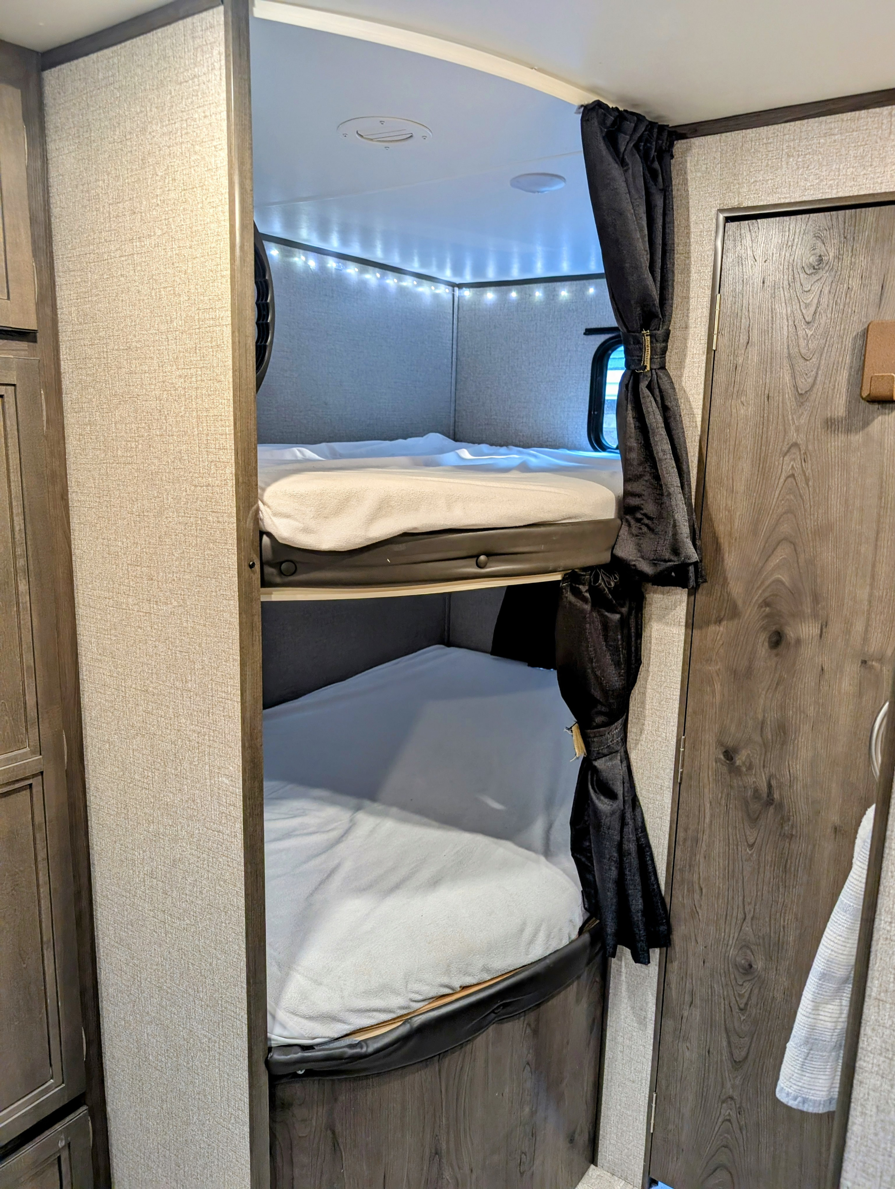 Cozy RV rental bunk beds with privacy curtains and ambient lighting, providing comfortable sleeping space inside a camper.. Jayco Jay Flight 2020