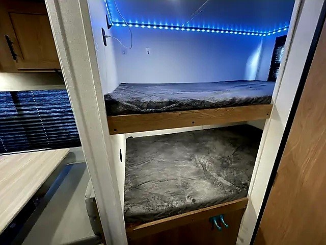 Cozy rv rental interior featuring compact bunk beds with vibrant blue LED lighting and window blinds.. Avenger Avenger Trailer 2022