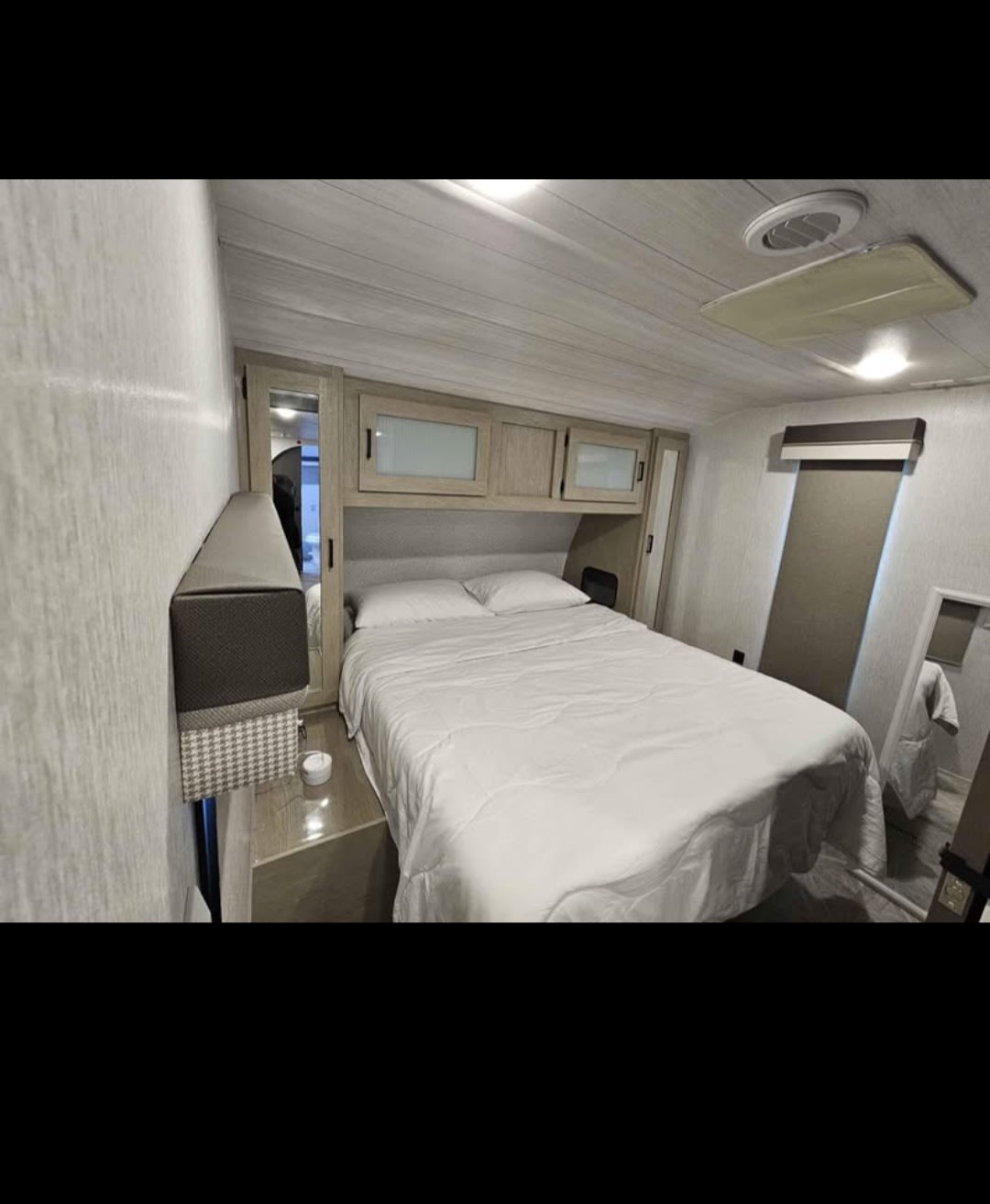 Cozy RV rental bedroom featuring a queen bed, overhead storage, and a full-length mirror for your travels.. Forest River RV 22RBSX 2023