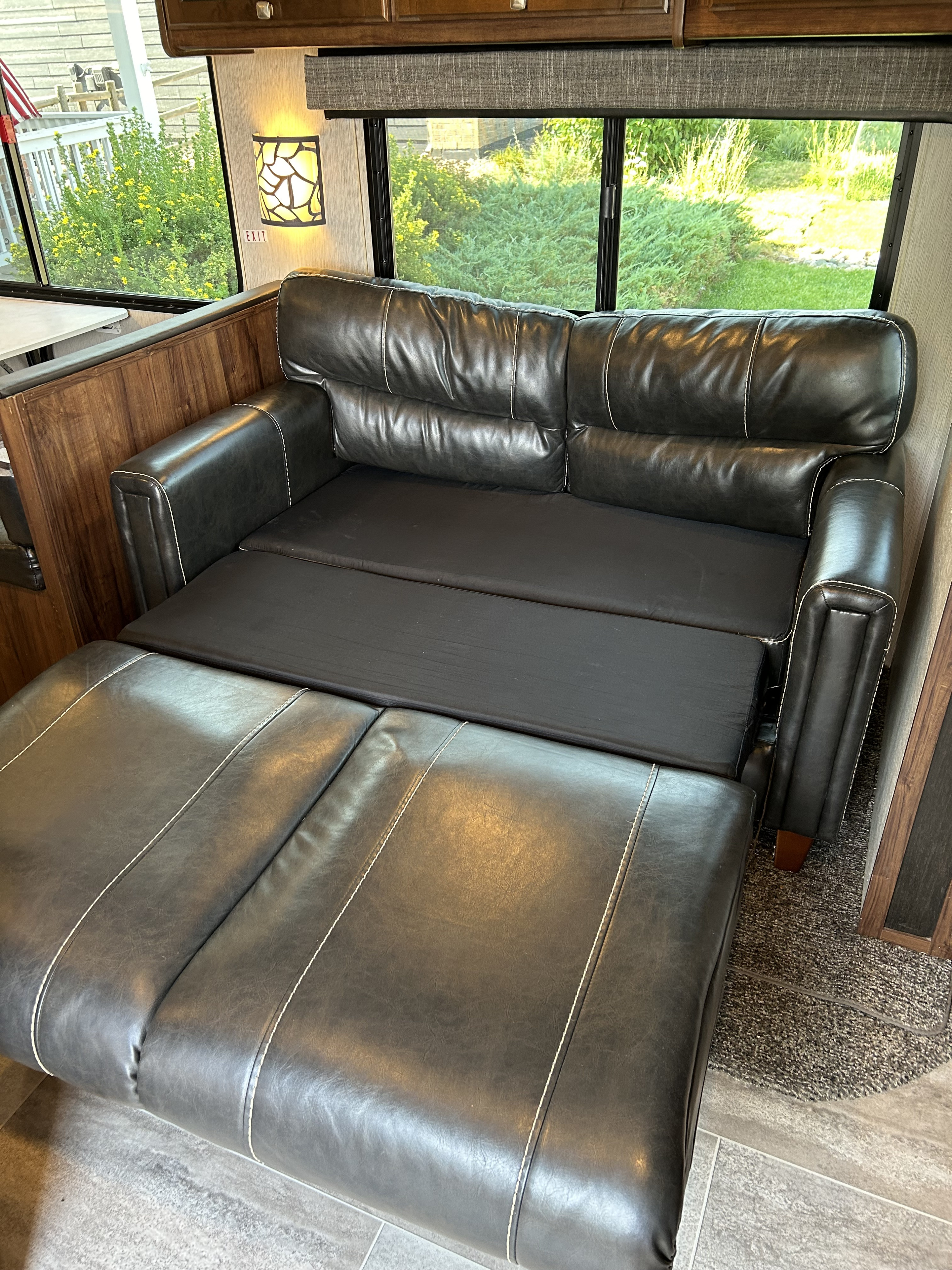 This RV rental's black leather sofa extends into a comfortable bed, offering flexible sleeping for your travels.. Heartland RVs Mallard 2019