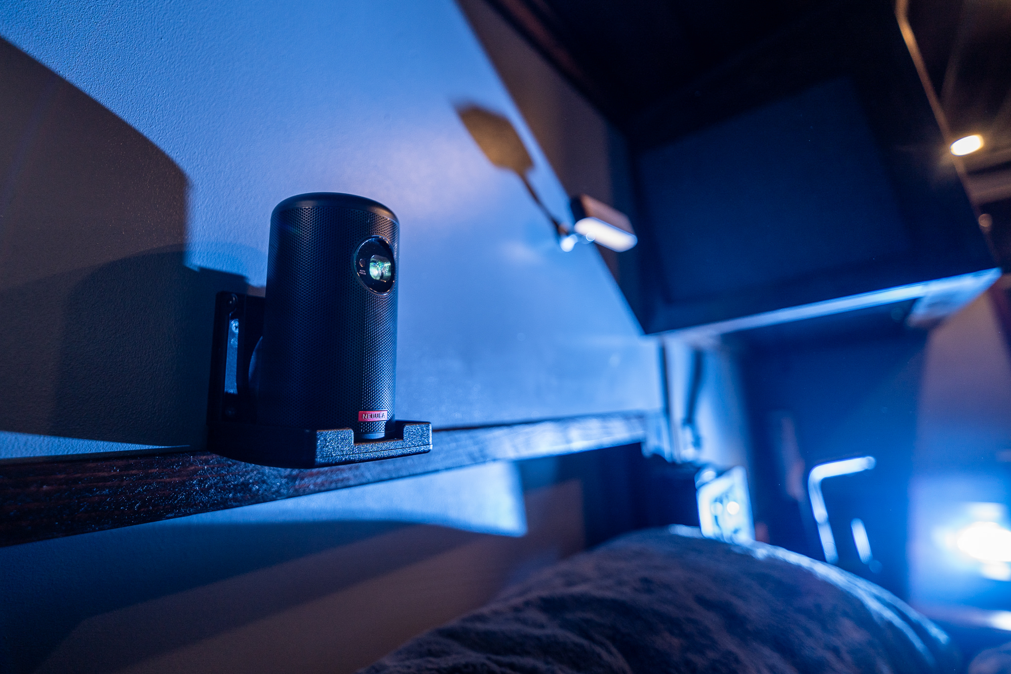 Compact projector on a shelf, providing entertainment in an RV rental. Blue ambient light creates a cozy vibe.. Ford Transit 350 HD XL 2020