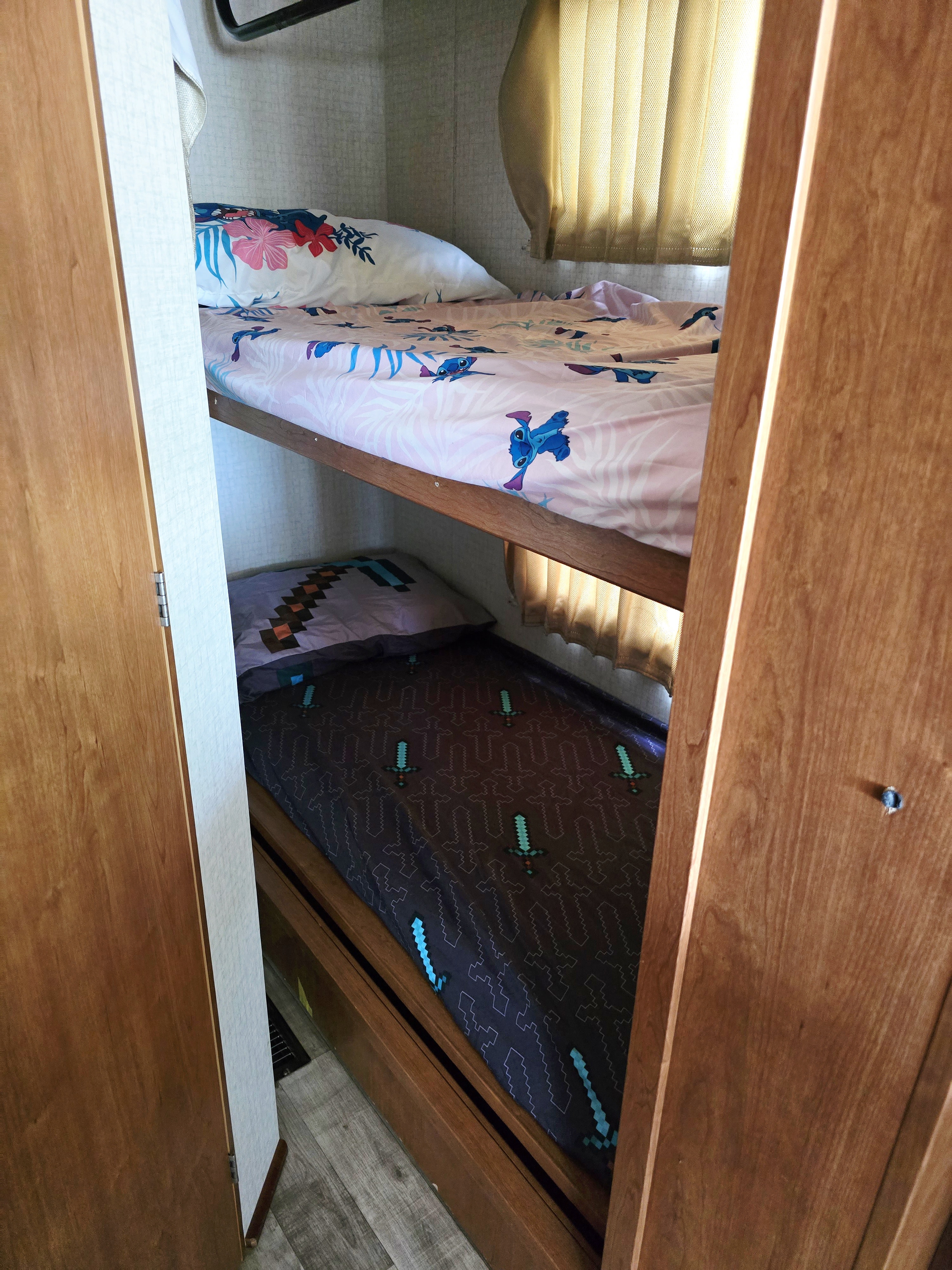Interior of an RV rental showing two themed bunk beds: upper with Stitch, lower with Minecraft bedding.. Winnebago Vista 2017