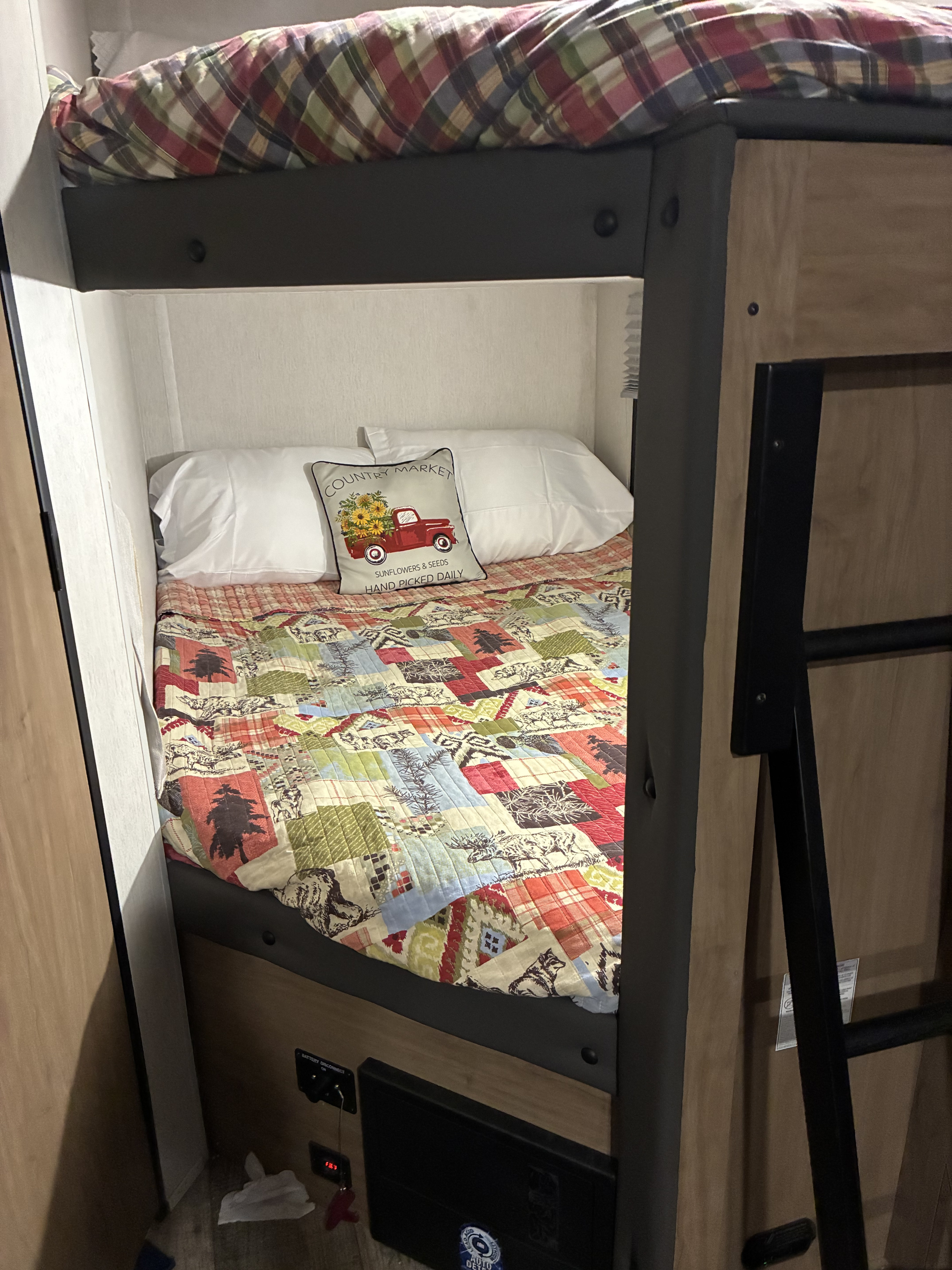 Comfortable bunk beds ready for adventure in this RV rental, with a charming quilt and a cozy plaid top bunk.. Forest River Cherokee Grey Wolf 2024