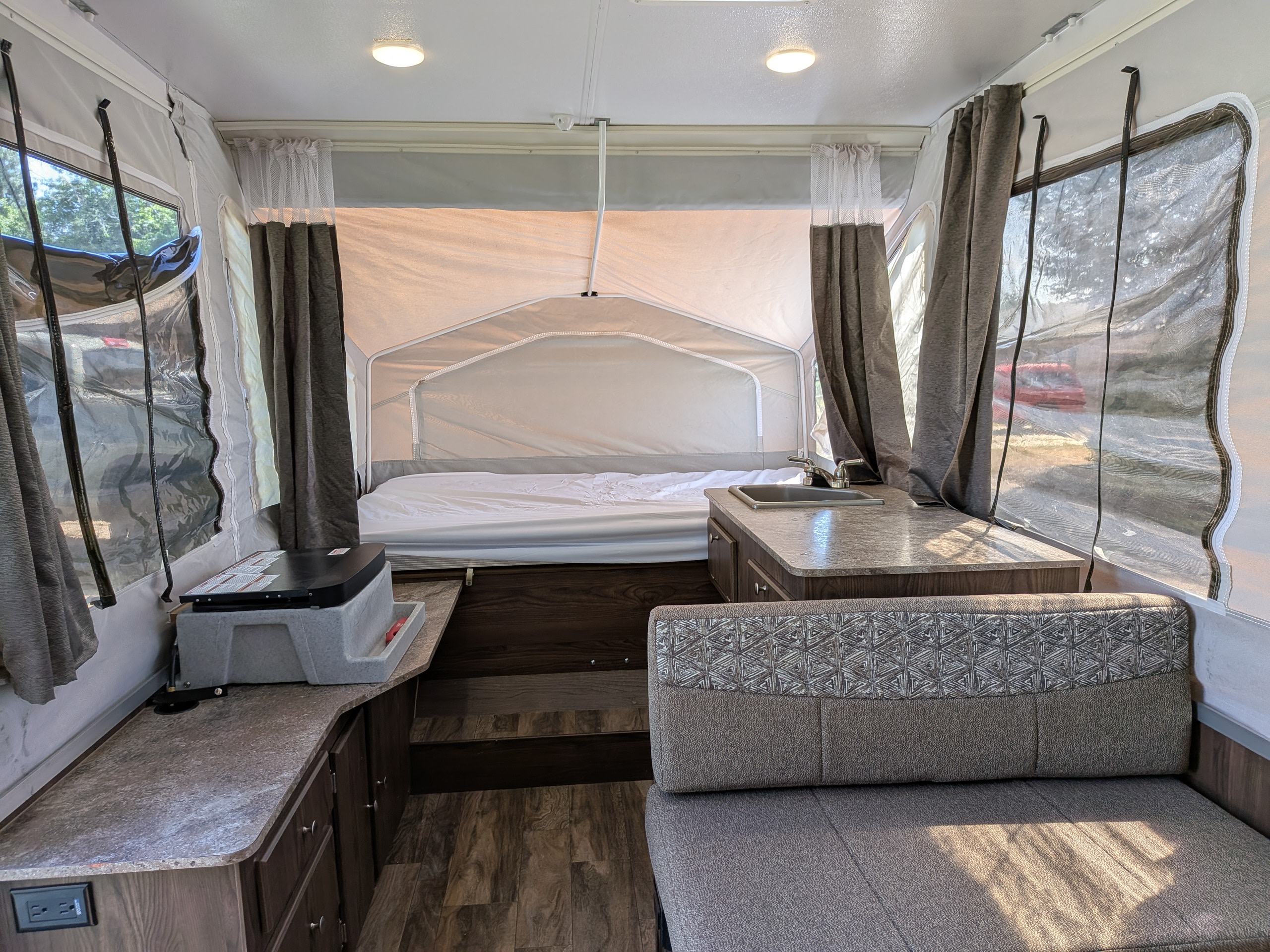 Spacious pop-up RV rental interior with a bed, kitchenette, and dinette, perfect for comfortable camping adventures.. Forest River Flagstaff M.A.C. 2018
