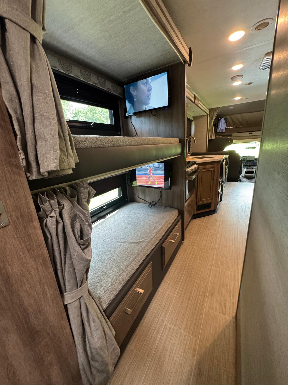This RV rental features comfy bunk beds with individual TVs, a galley, and a spacious interior hallway.. Entegra Coach Odyssey 2021