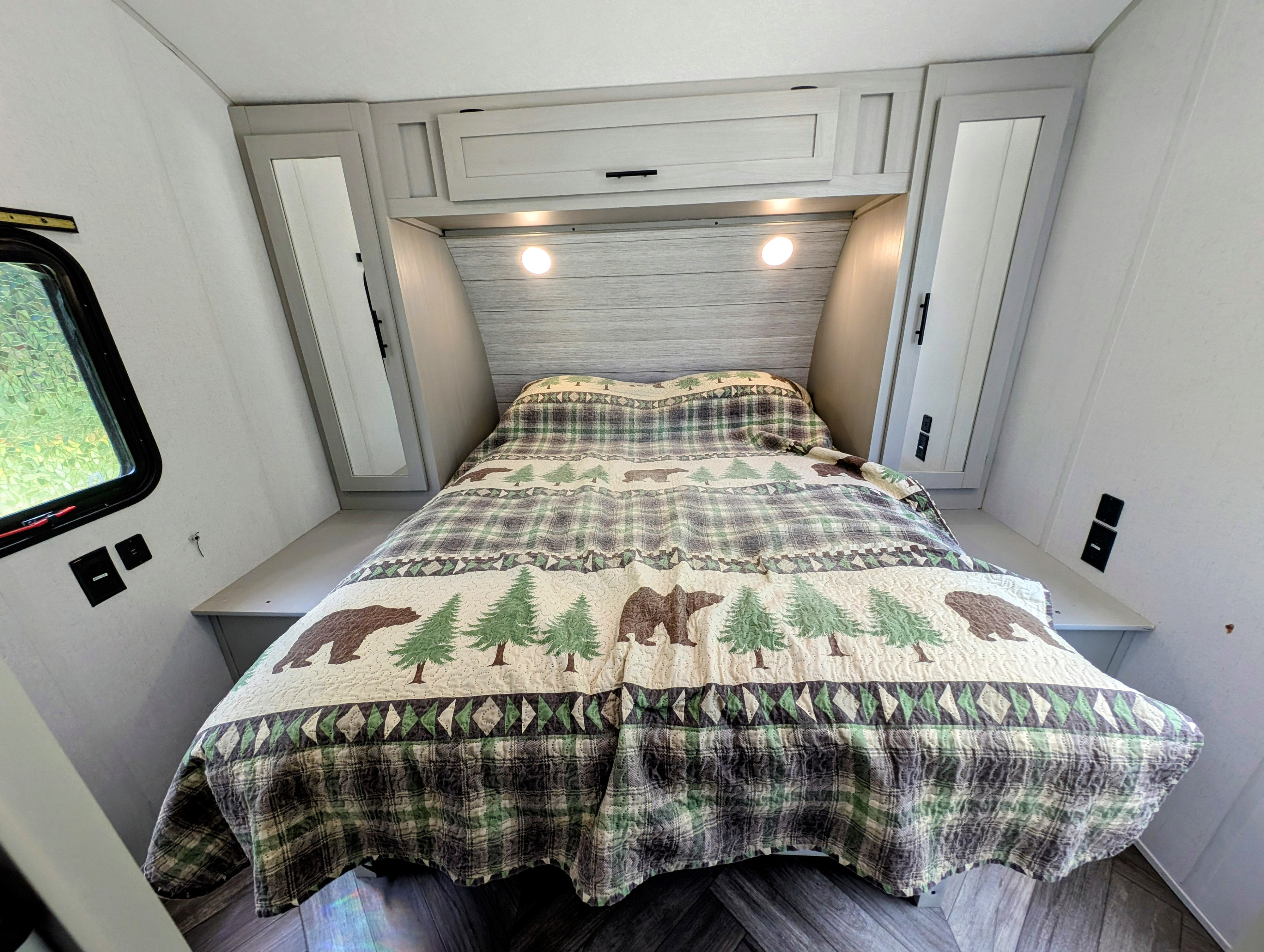 Inside a comfortable RV rental, featuring a bed with a charming bear and tree quilt, reading lights, and convenient storage.. Forest River Salem 2021