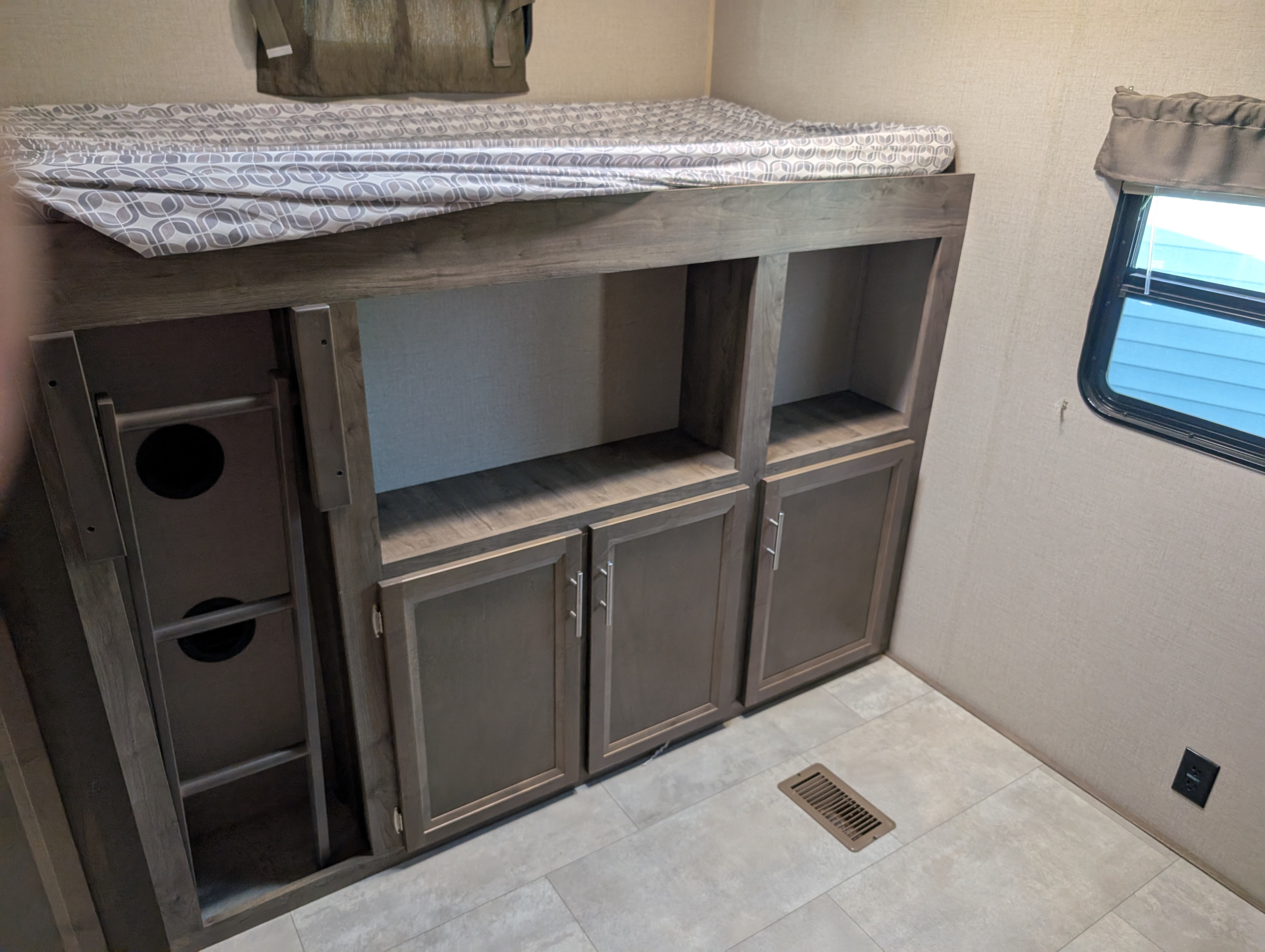 This RV rental features comfortable bunk beds with patterned bedding, built-in storage, a ladder, and a window.. Forest River Coachmen Aurora 2022
