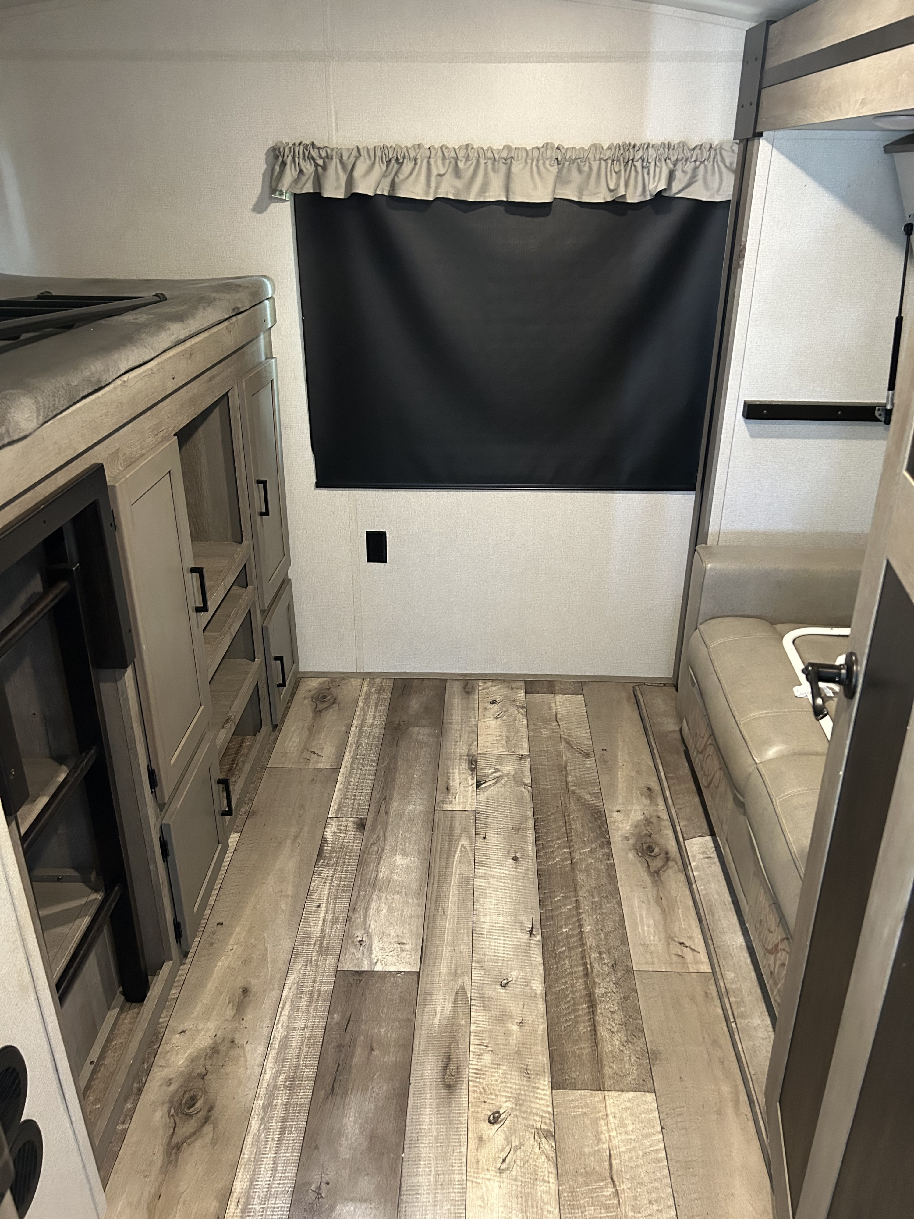 RV rental interior: bunk bed with storage, window, sofa, and wood-look flooring.. Keystone Outback 2021
