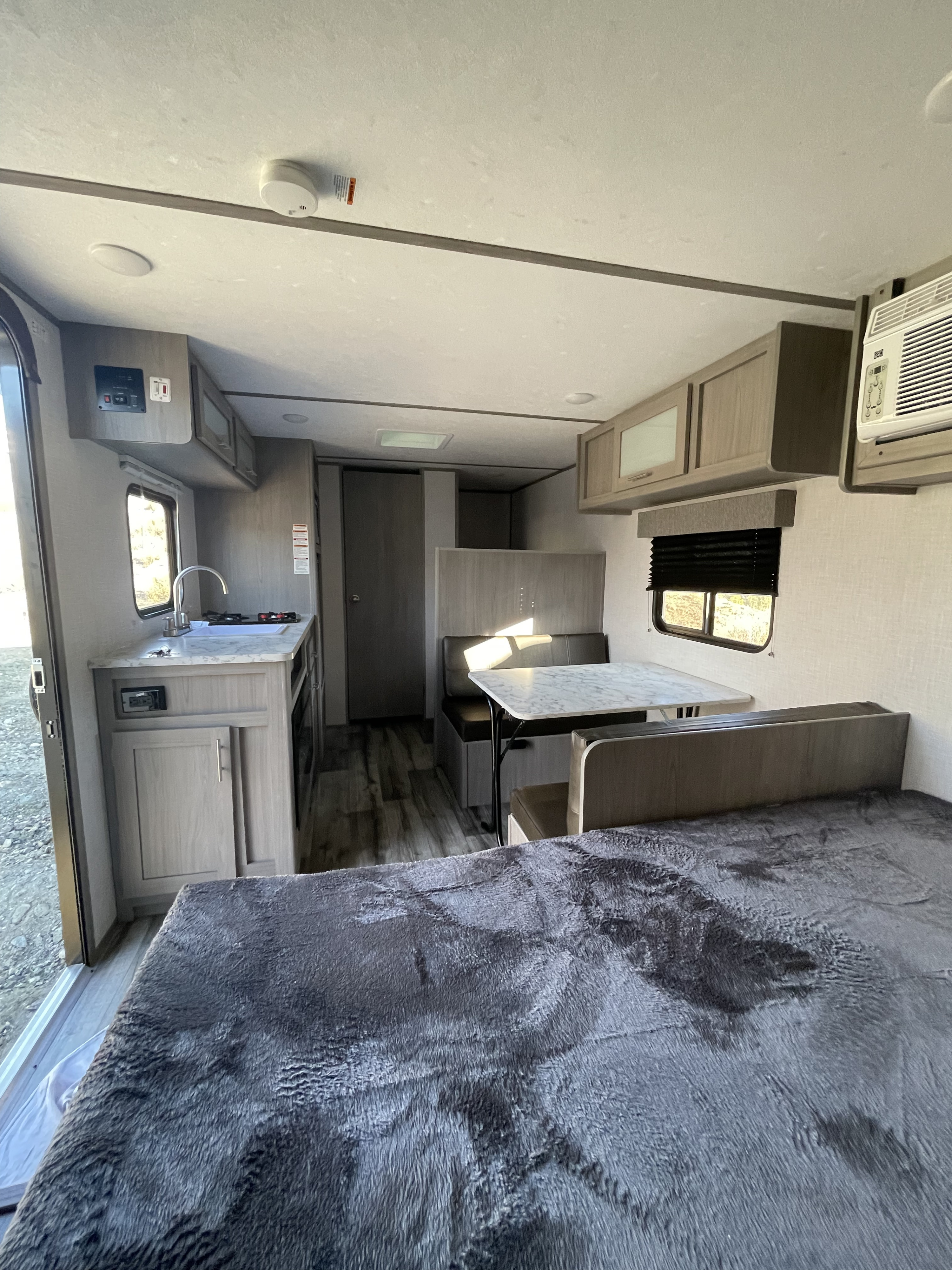 Modern RV rental interior: cozy bed, kitchen, and dining area with ample natural light, perfect for your next adventure.. Dutchmen Coleman Lantern LT 2022